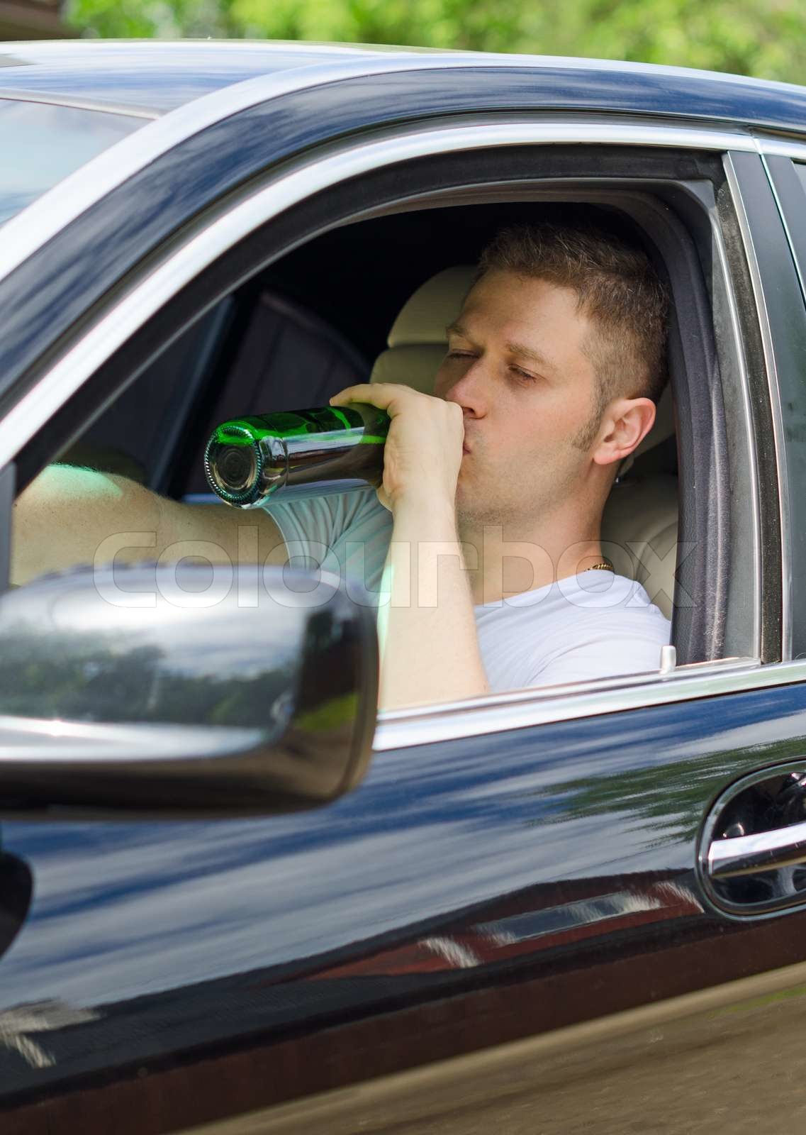 Driving Under the Influence. Man drinking alcohol in the car. Stock image Colourbox