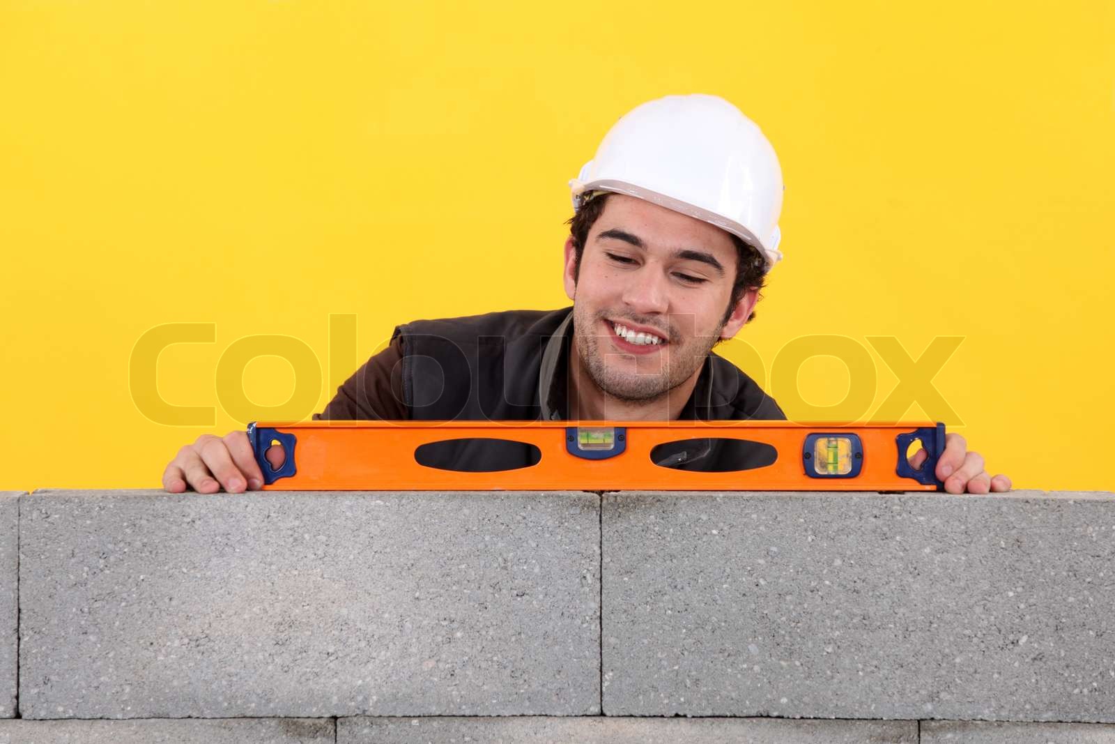 UpBeat Maurer mit Wasserwaage an Wand Stock Bild Colourbox