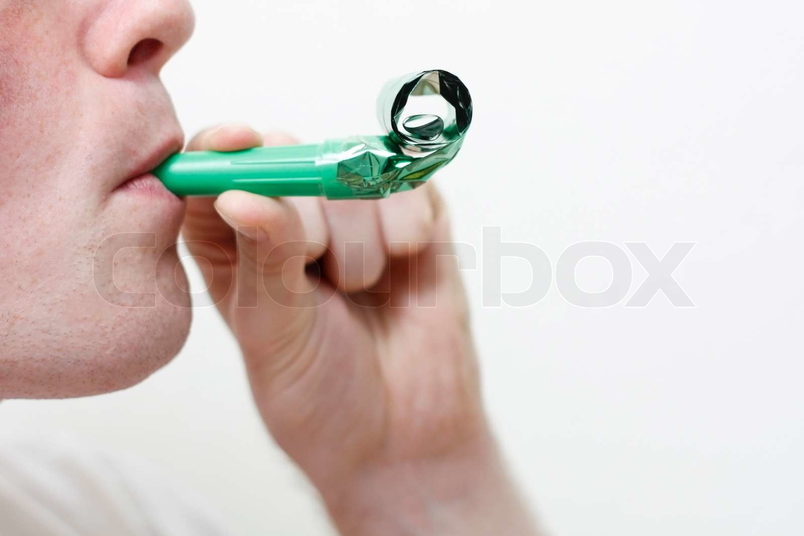 A man blowing a party horn | Stock image | Colourbox