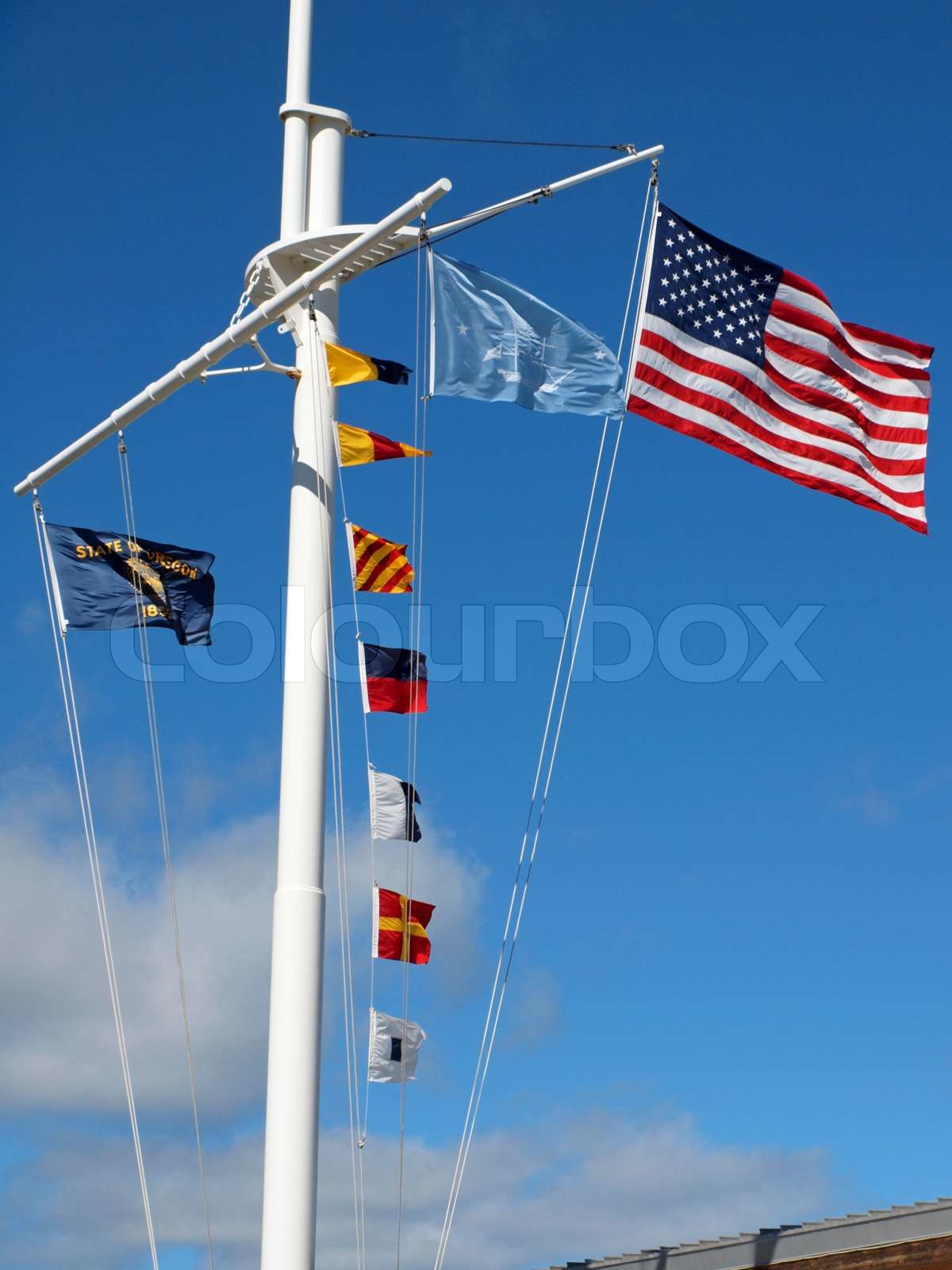 Nautical and American Flags Hanging from a Ship's Mast with Wispy