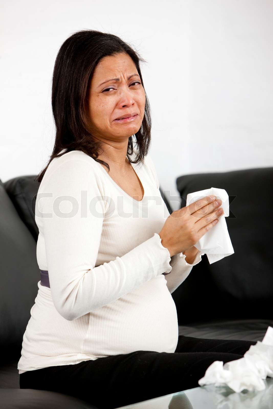 A crying pregnant woman on a sofa | Stock image | Colourbox
