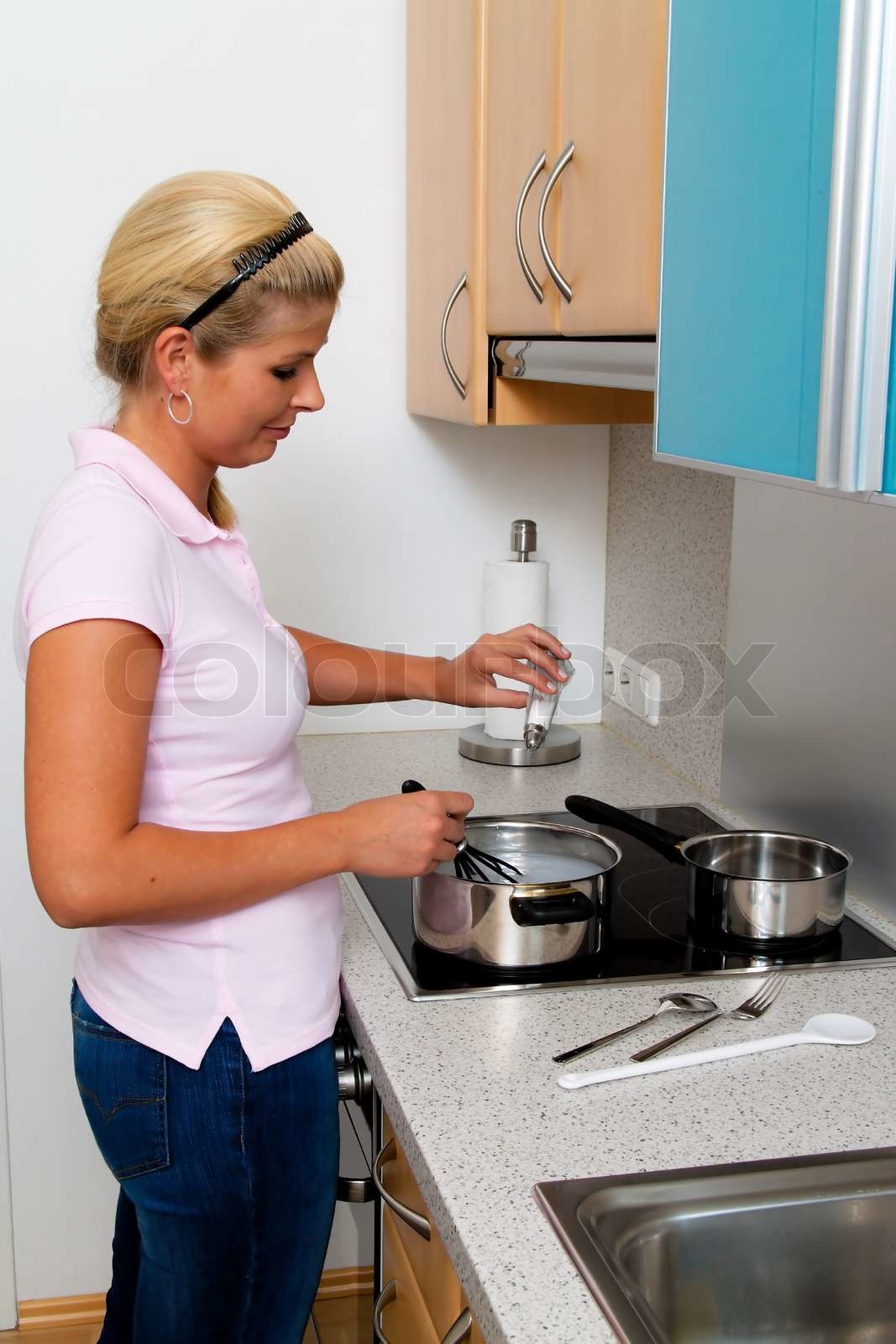 A woman in the kitchen while cooking with electric stove Stock image