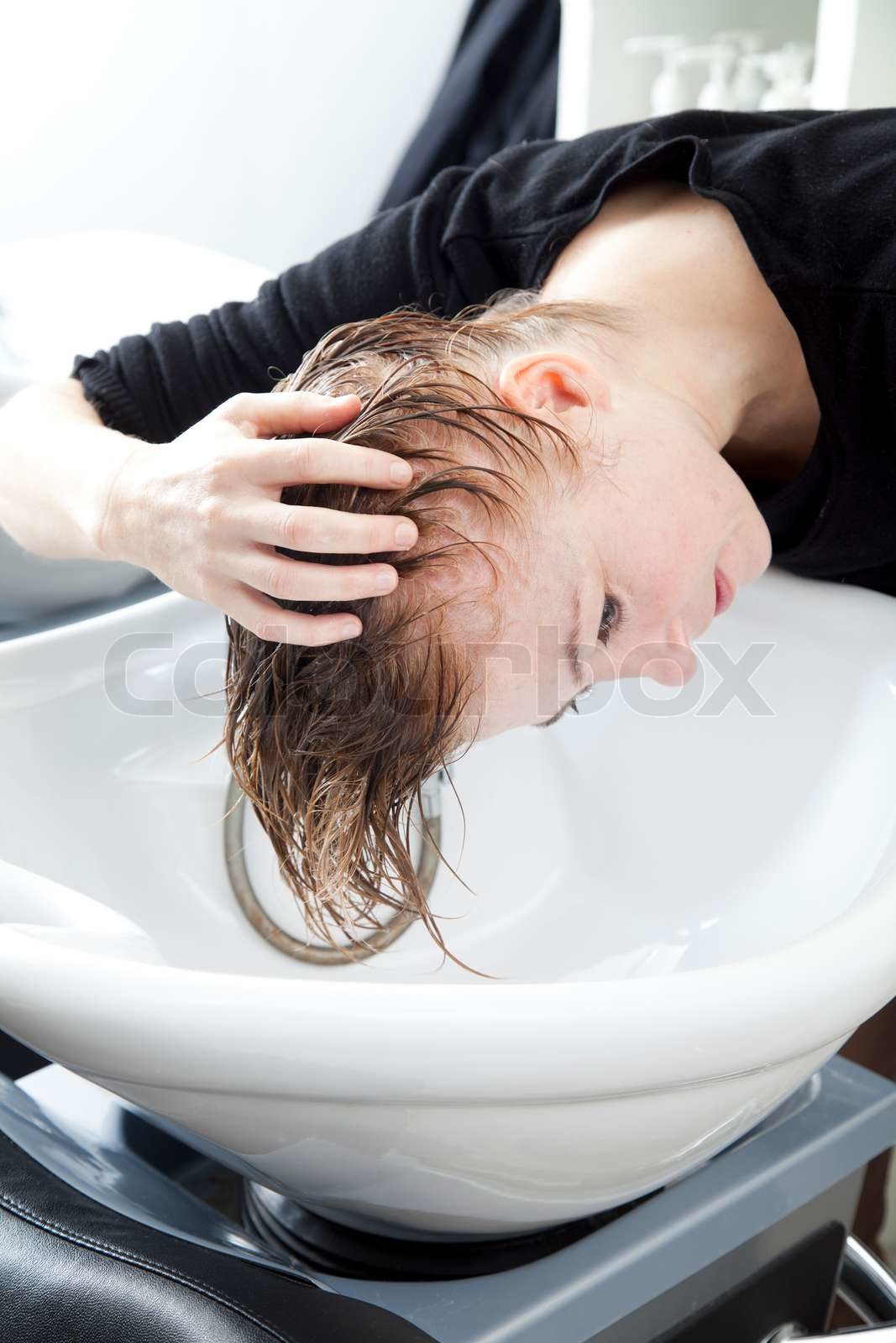 A woman washing her hair on a sink in a hair salon | Stock image
