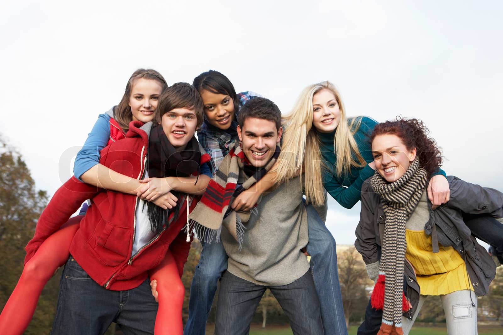 Gruppe af teenage venner under piggyback rides i efteråret Landskab ...