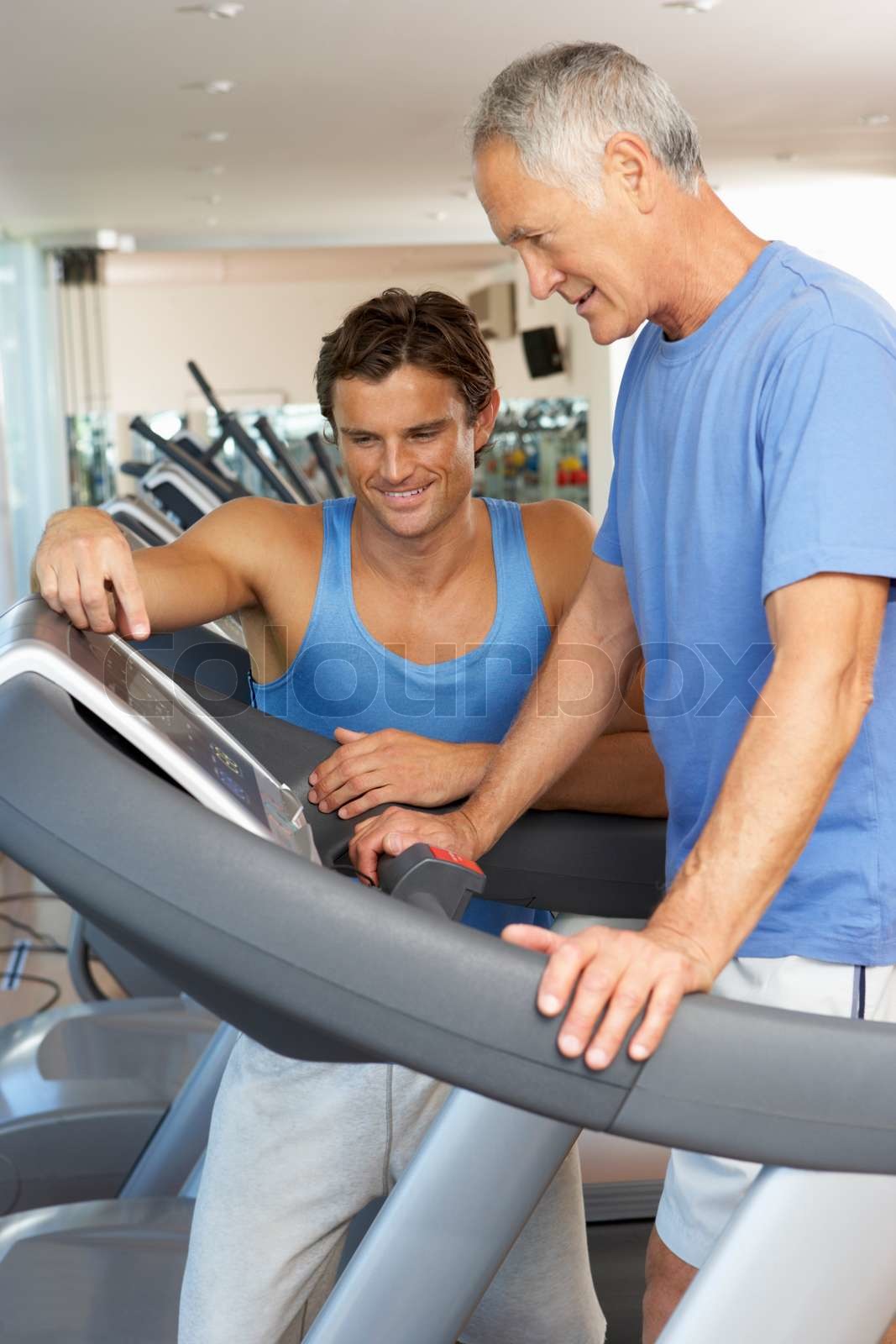 Man Arbeiten mit Personal Trainer On Running Machine Im Gym Stock