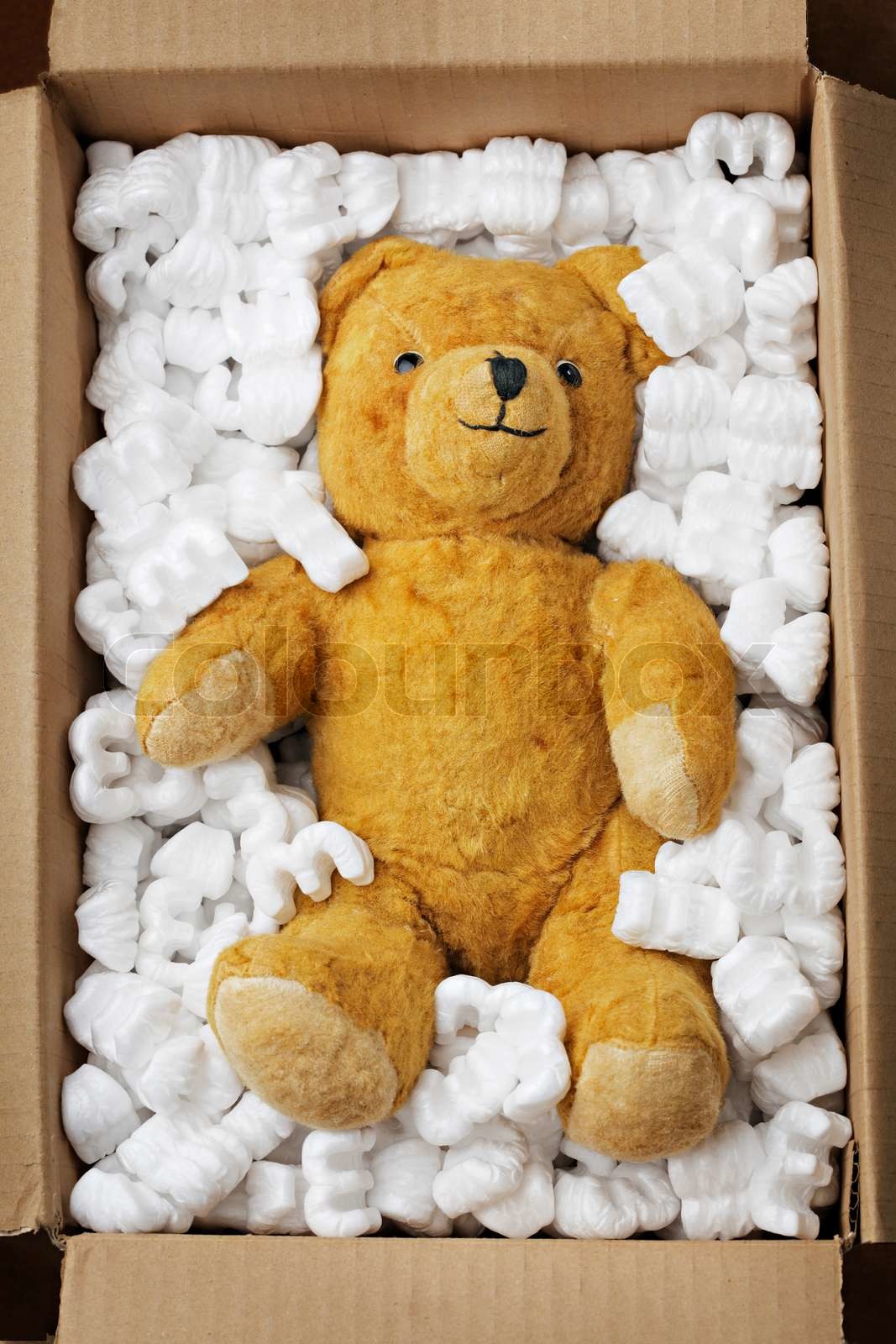 Old teddy bear in a cardboard box with styrofoam packaging Stock
