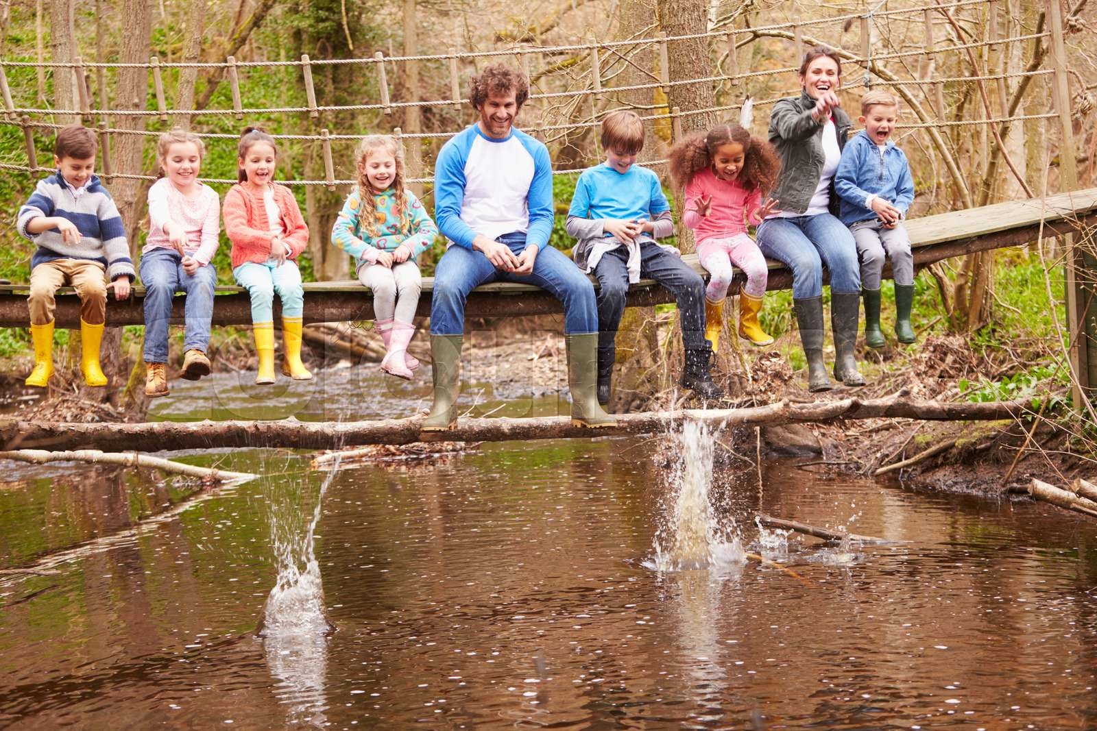 adults-with-children-on-bridge-at-outdoor-activity-centre-stock-image