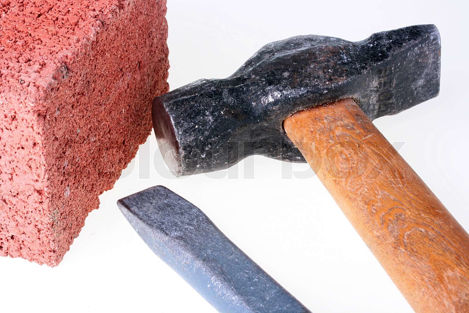 Byggematerialer og værktøjer en mejsel og en hammer med en mursten fra