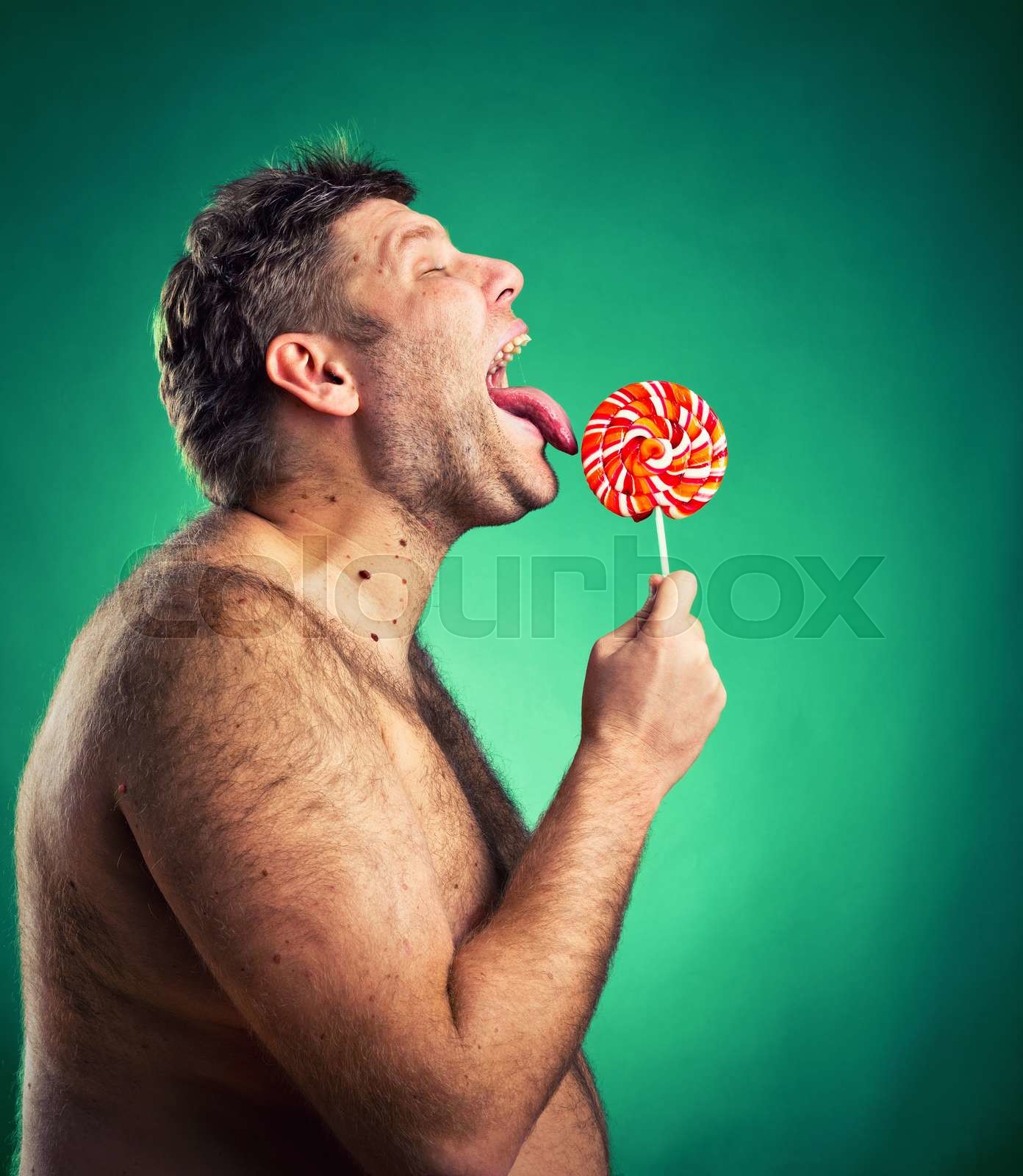 Shirtless man licking candy | Stock image | Colourbox
