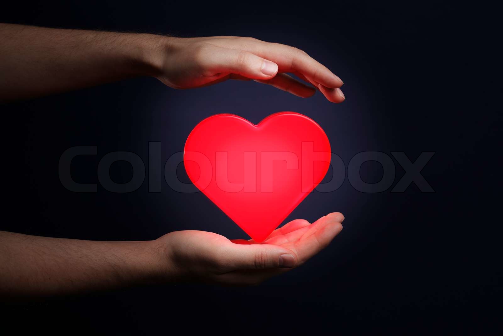 Man holding a red glowing heart in his hands | Stock image | Colourbox