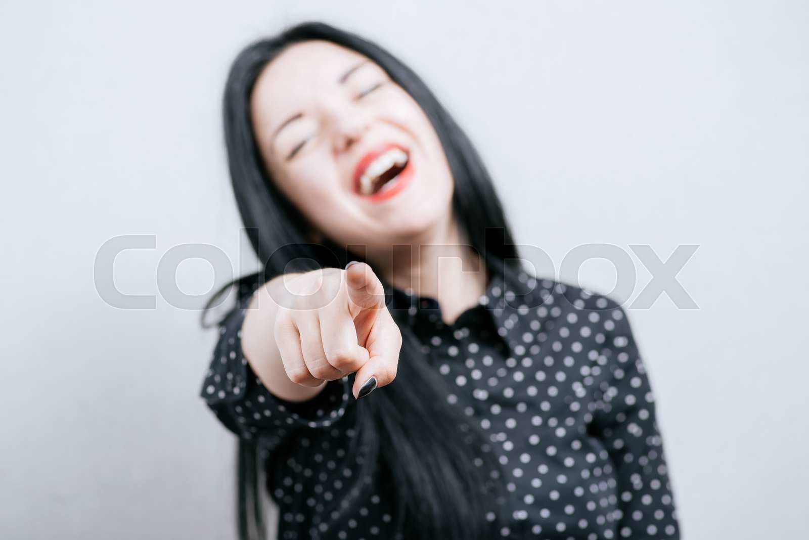 Woman laughing and pointing at someone | Stock image | Colourbox