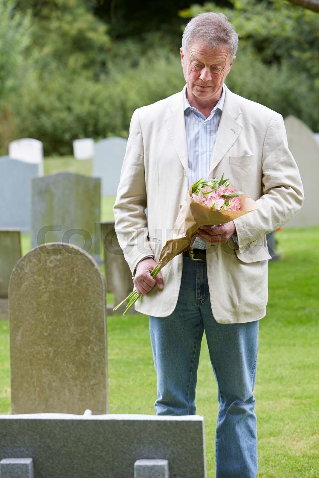 Man Laying Flowers on Grave | Stock image | Colourbox