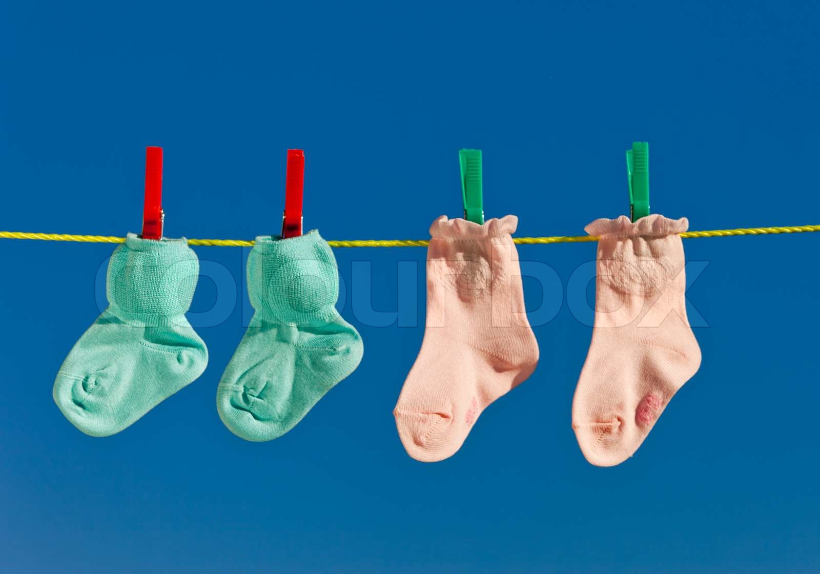 Baby socks on clothesline to dry. Blue sky. Stock image Colourbox