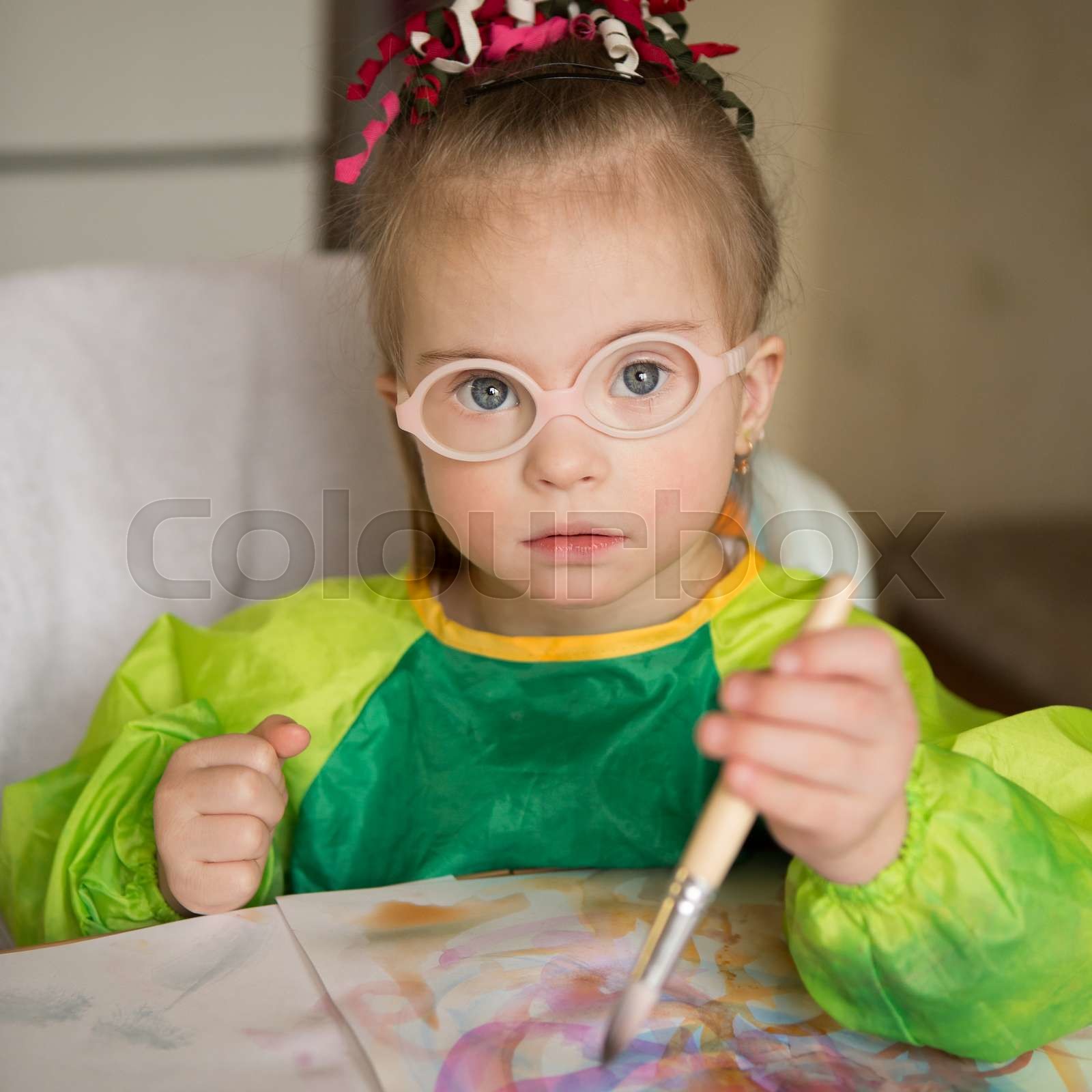 Girl with Down syndrome covered in paint when drawing | Stock image