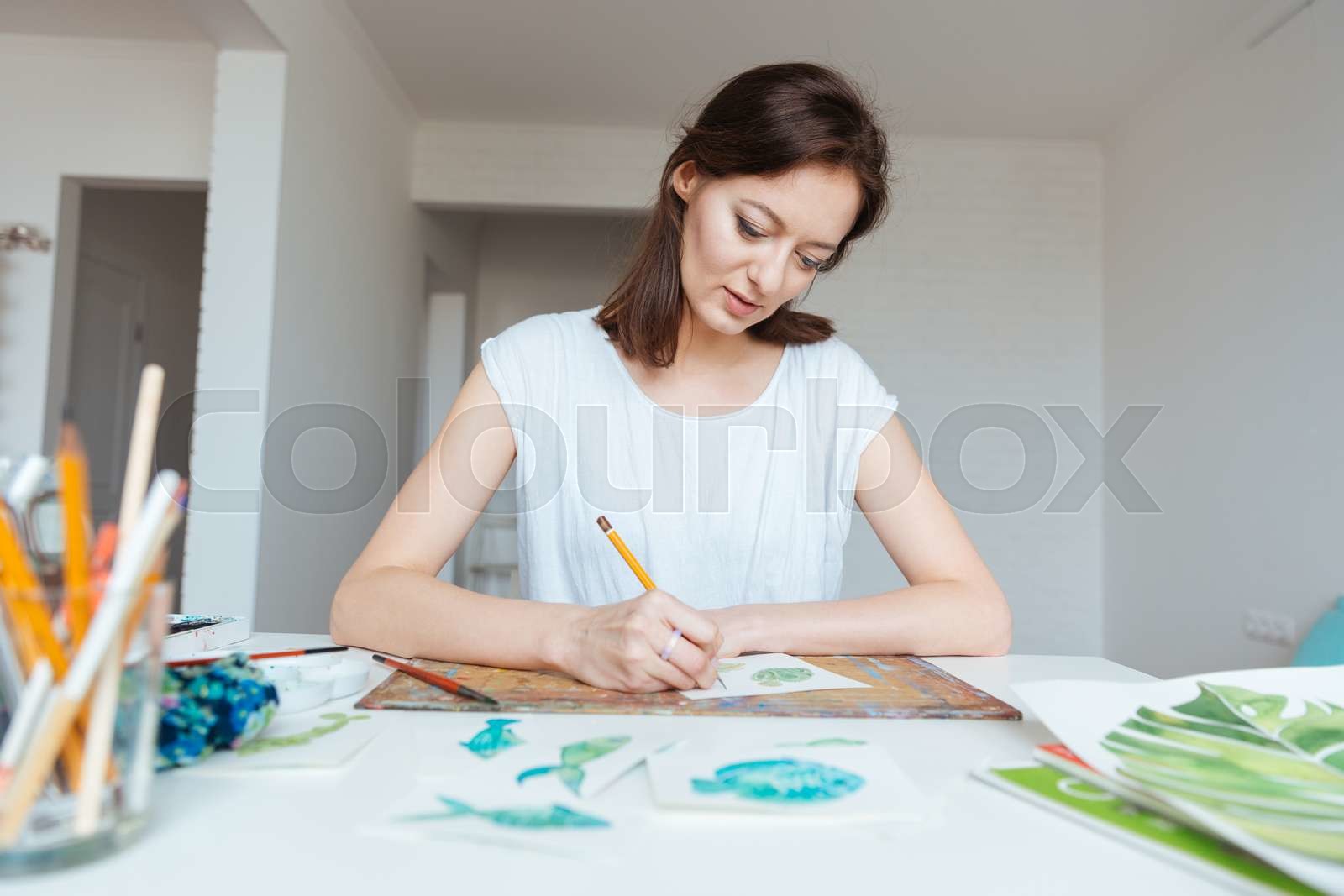 Concentrated woman painter making sketches with pencil in art studio
