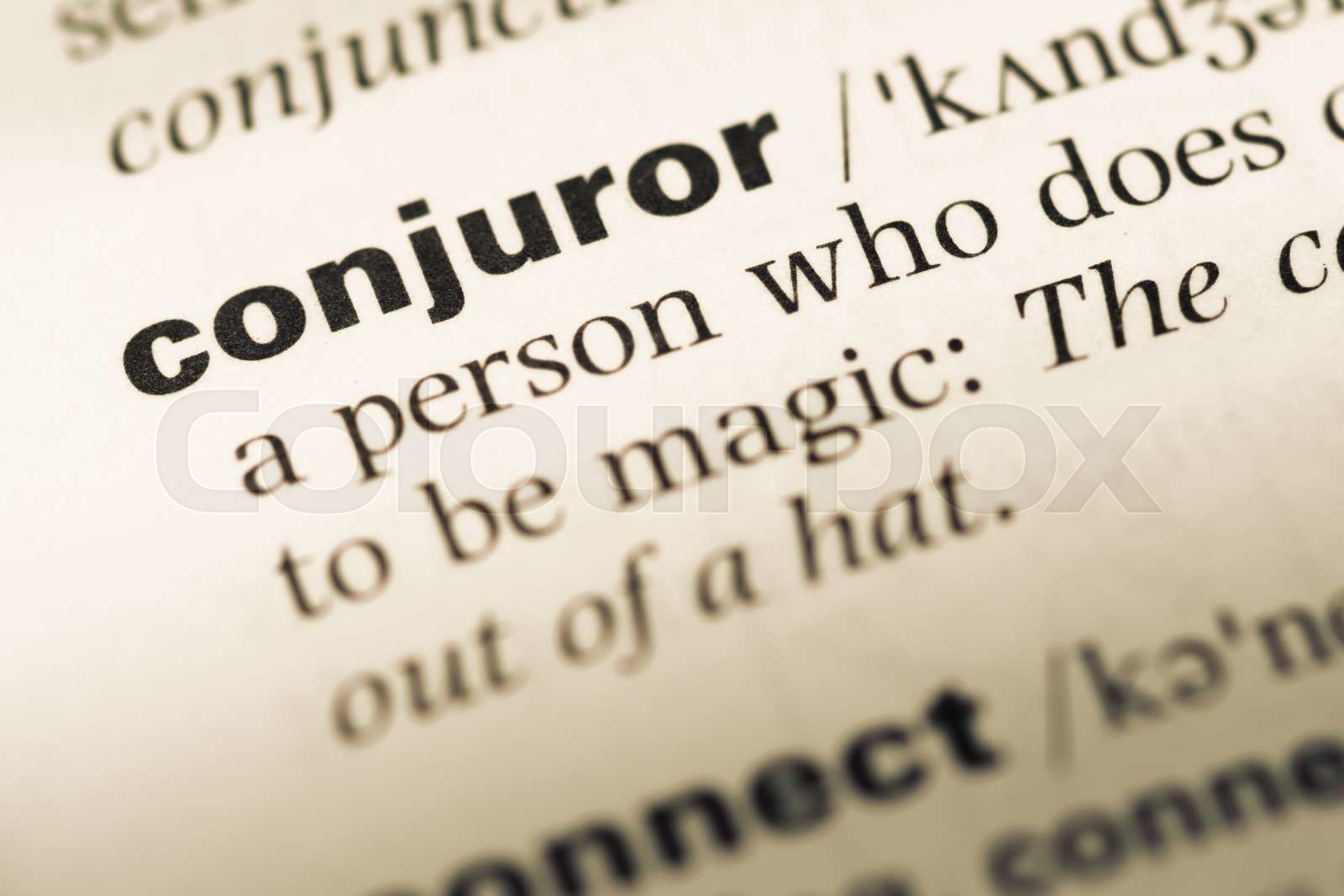 Close up of old English dictionary page with word conjuror. Stock