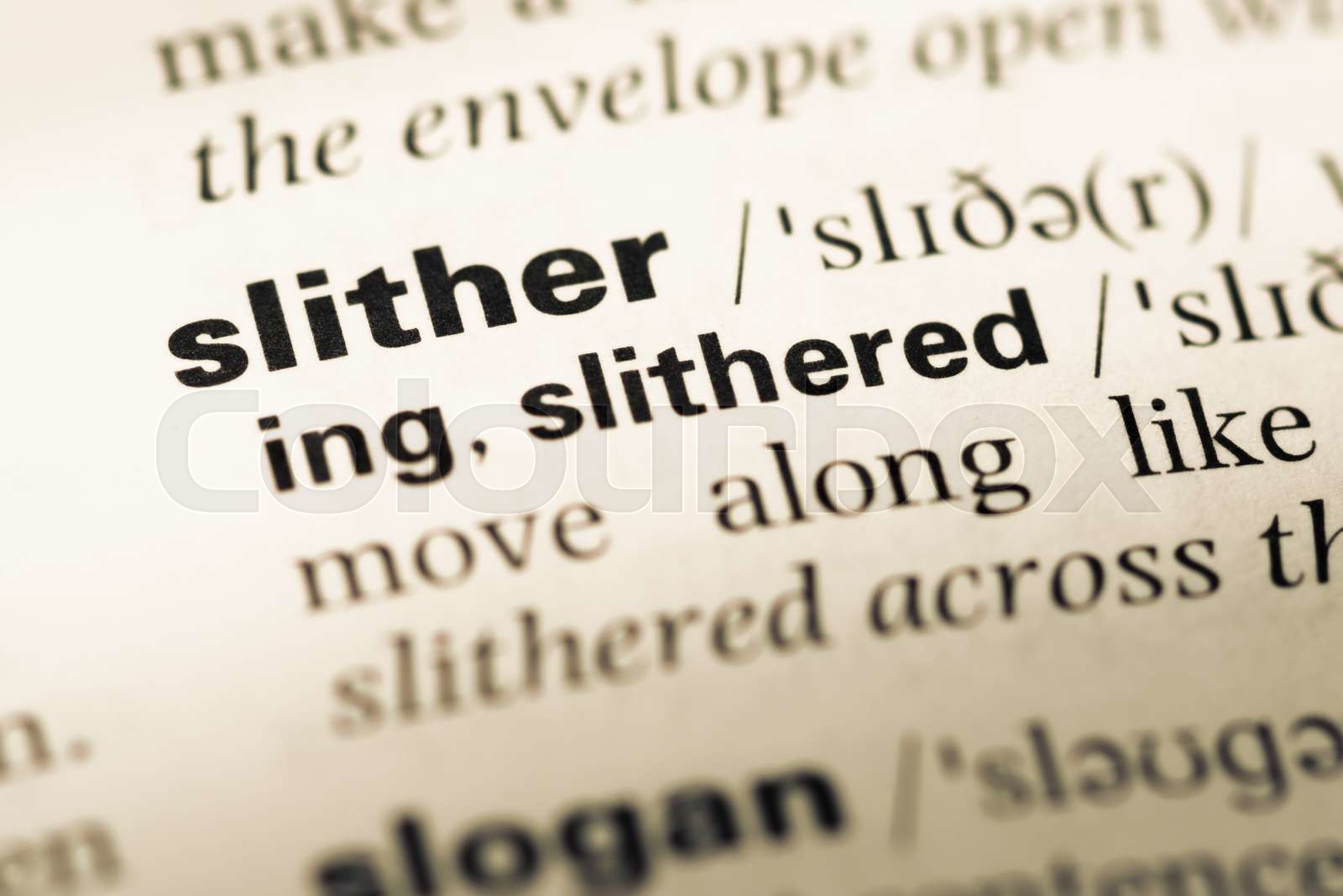 Close up of old English dictionary page with word slither. | Stock