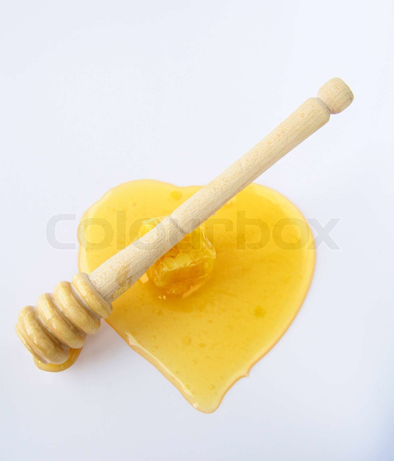 Honig tropft aus einem hölzernen Honiglöffel auf weißem Hintergrund
