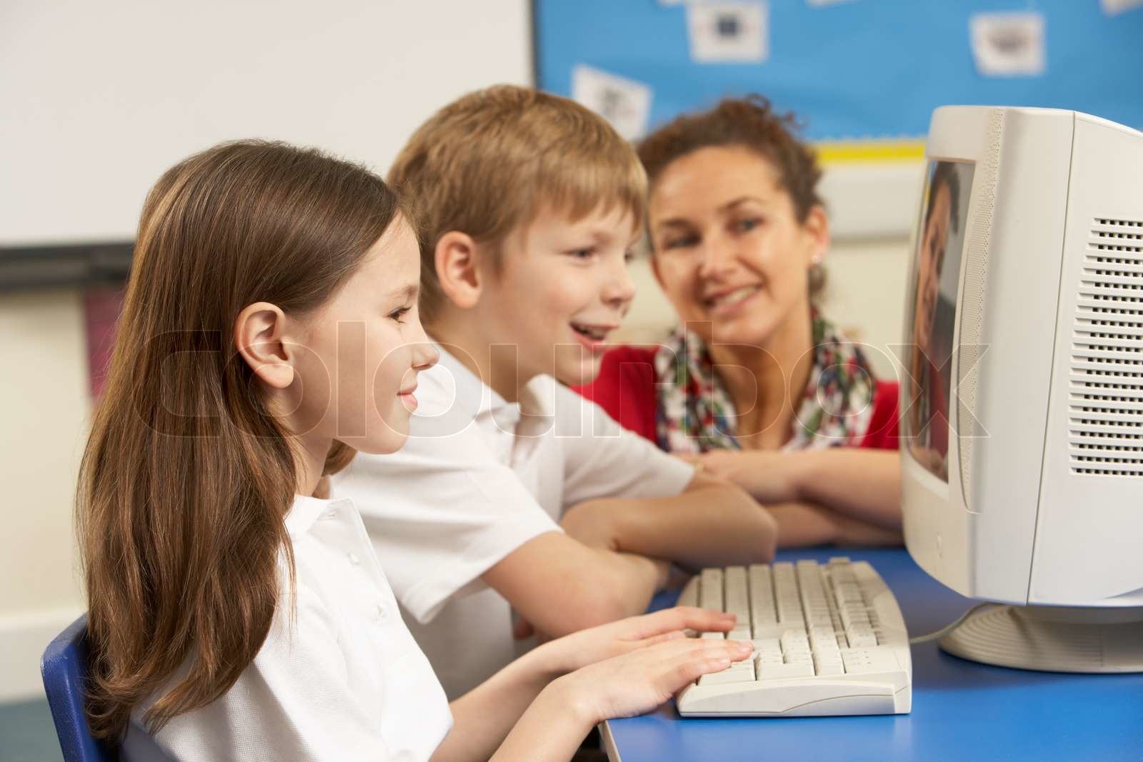 Schoolchildren In IT Class Using Computer with teacher | Stock image ...
