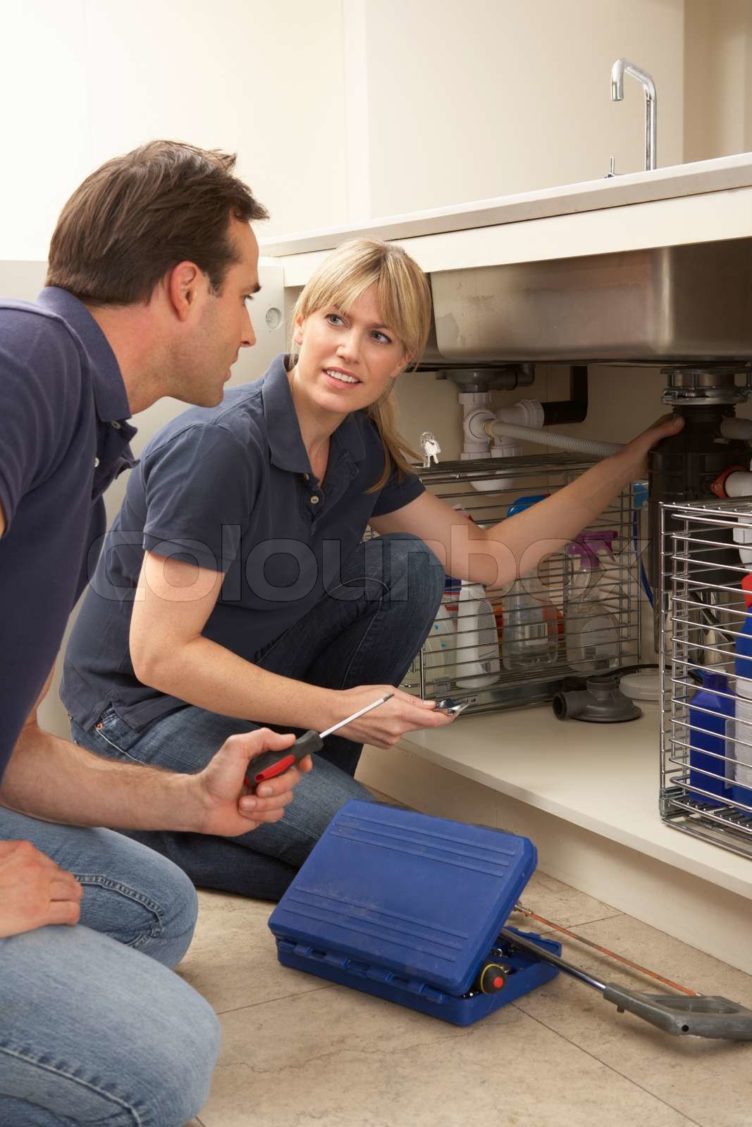 Plumber Teaching Apprentice To Fix Kitchen Sink In Home Stock Image