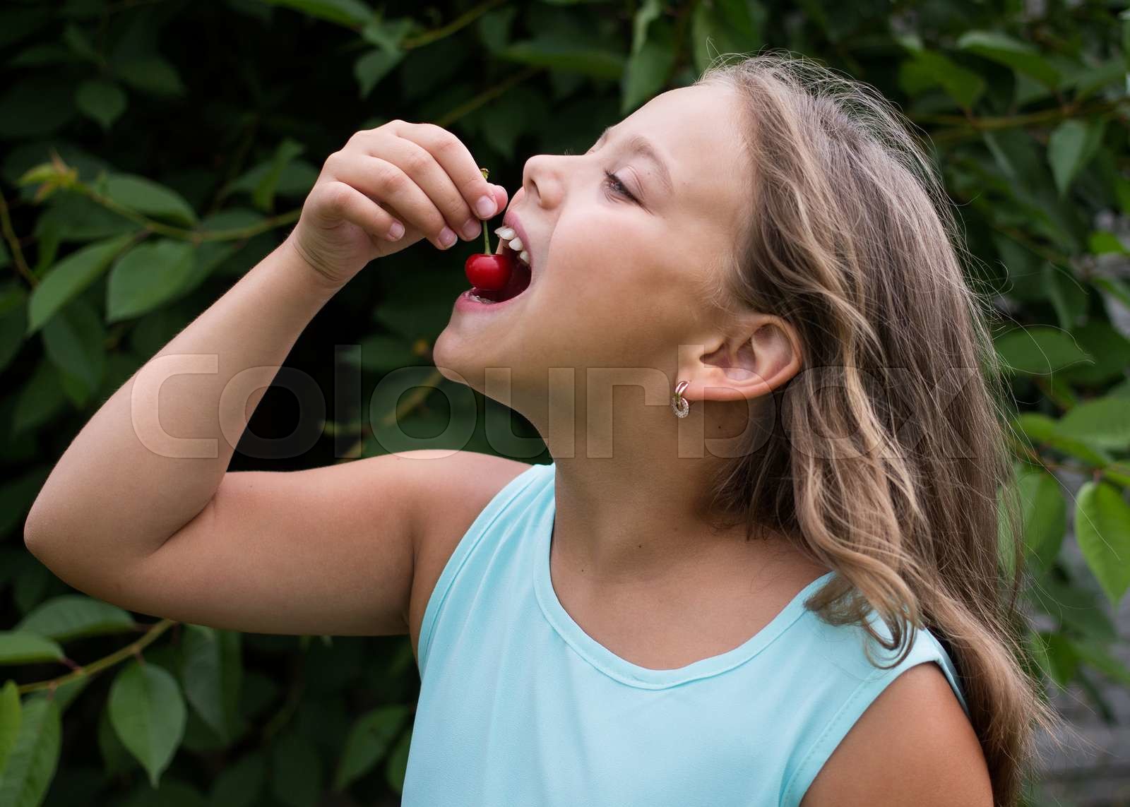 little girl eating a cherry Stock image Colourbox