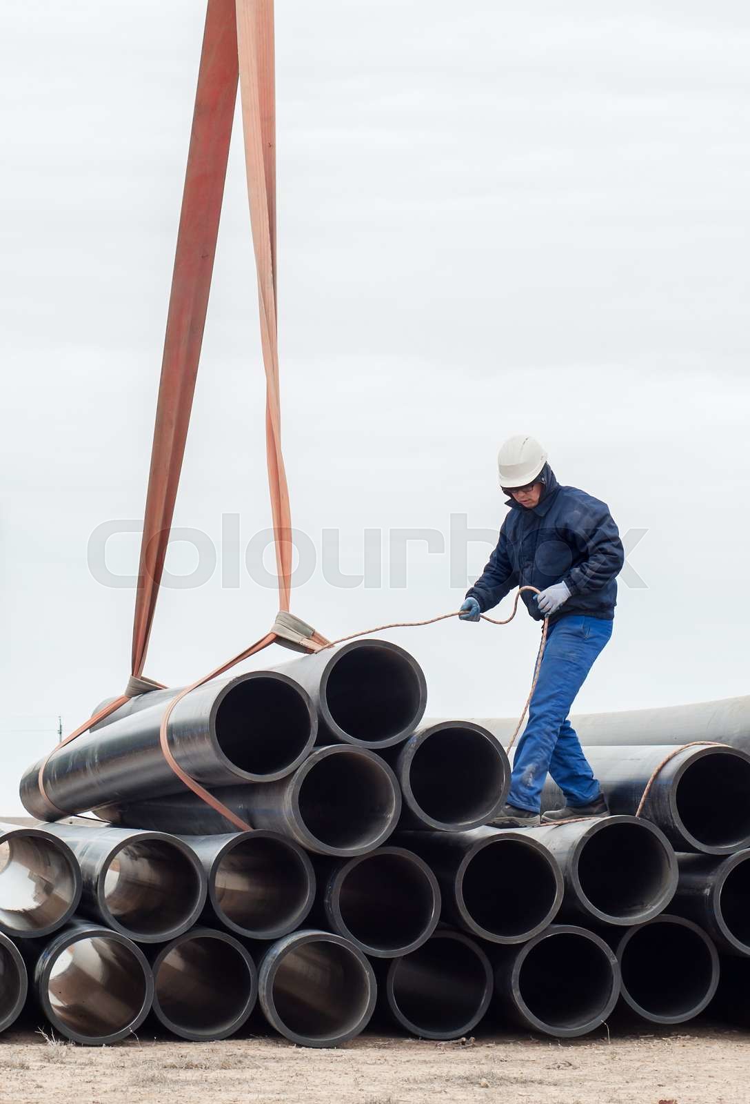 Crane mechanism in operation. Work on unloading of pipes for ...