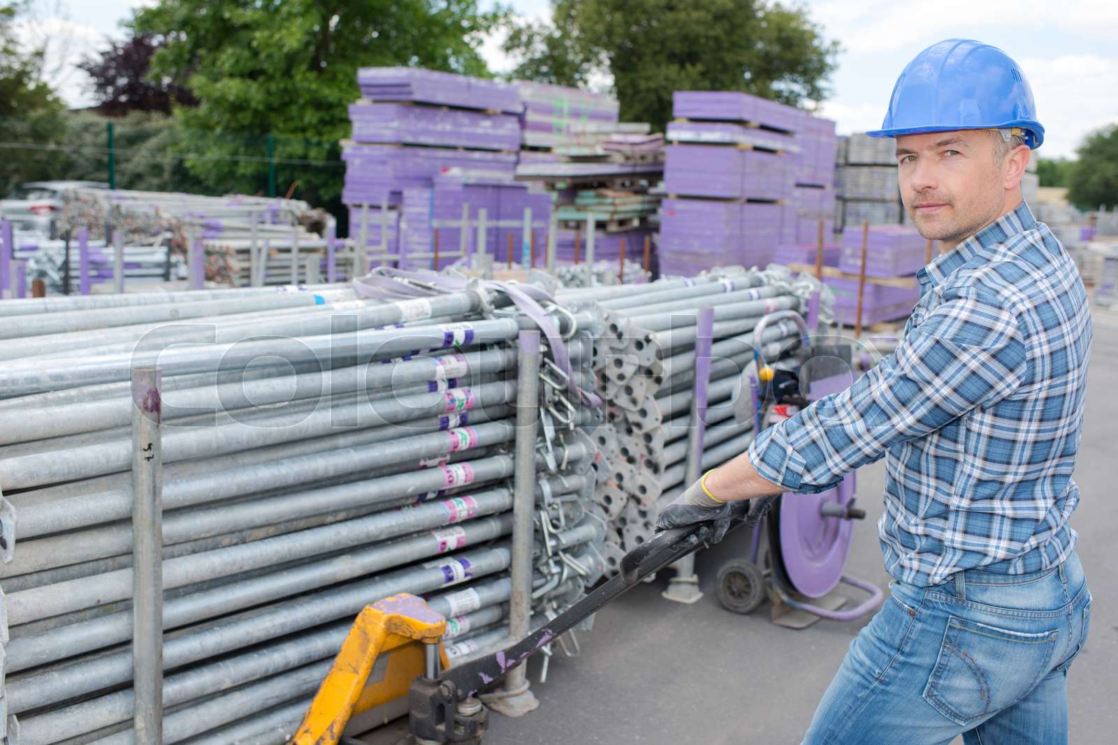 Worker pulling pallet of metal tubes | Stock image | Colourbox