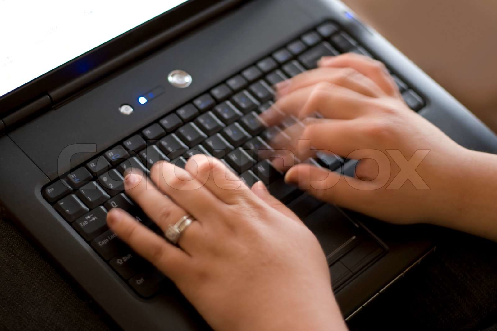 Detail of a woman typing rapidly on a laptop keyboard | Stock image