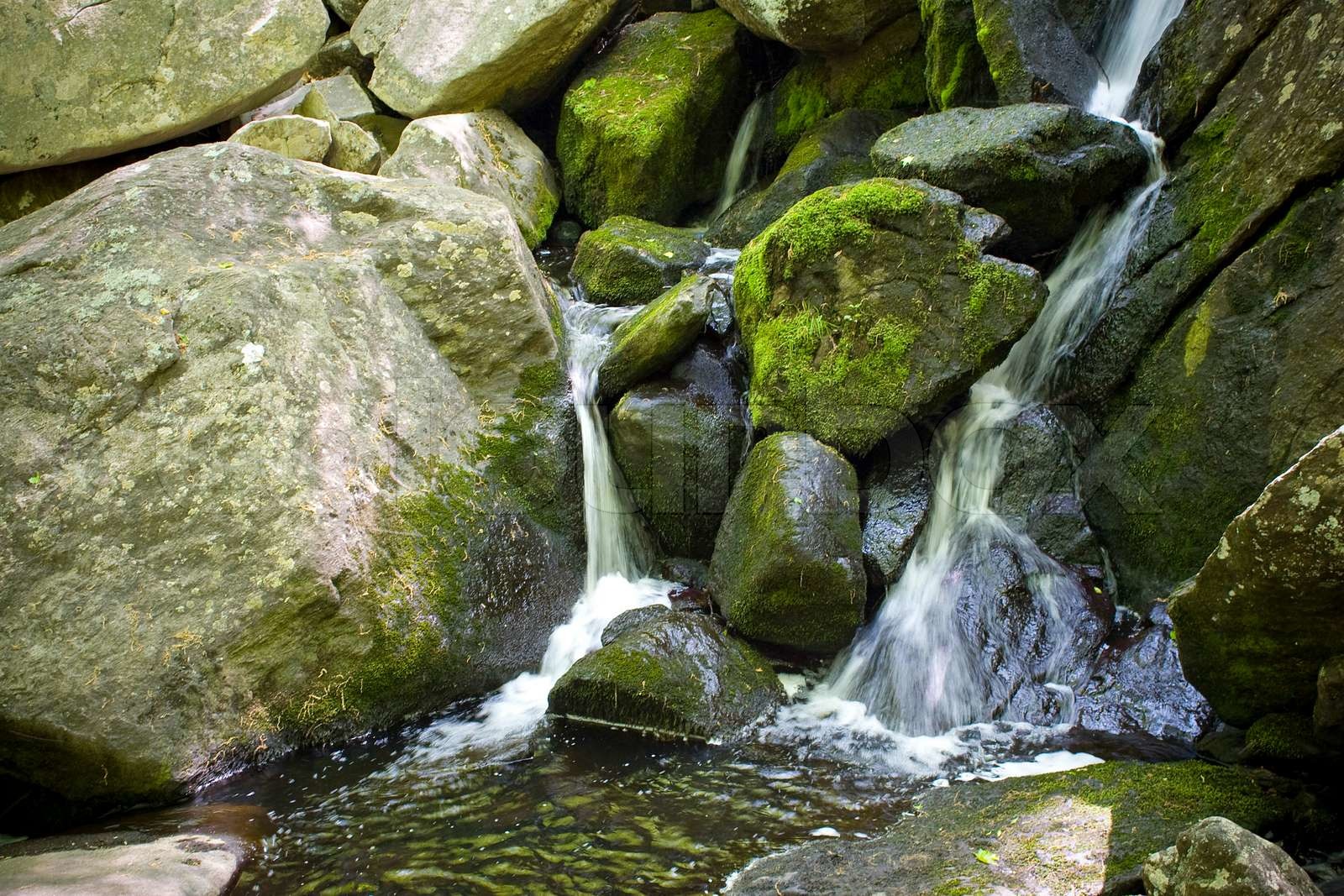 A beautiful waterfall flowing through some rocks in the woods | Stock ...