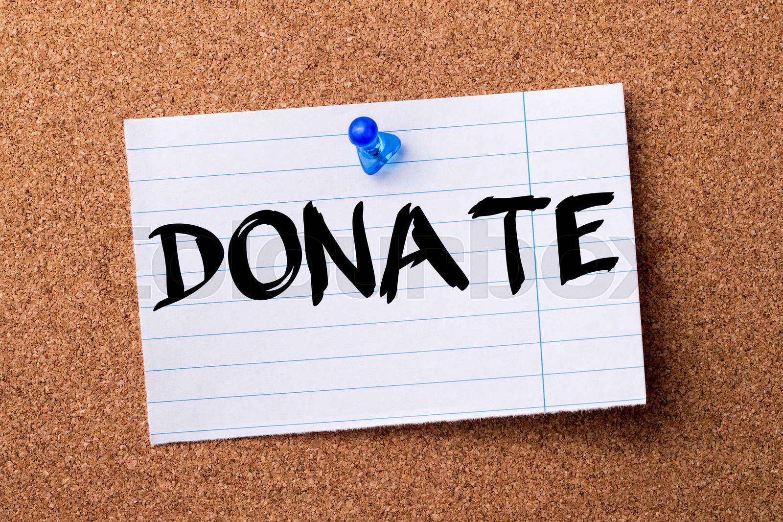 DONATE teared note paper pinned on bulletin board Stock image