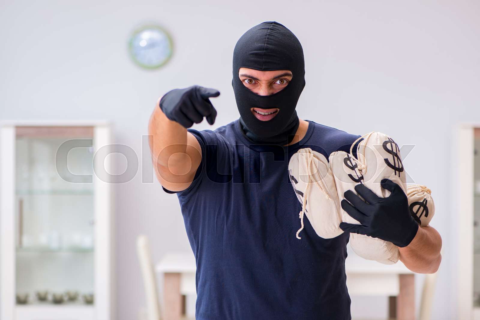 Robber wearing balaclava stealing valuable things | Stock image | Colourbox