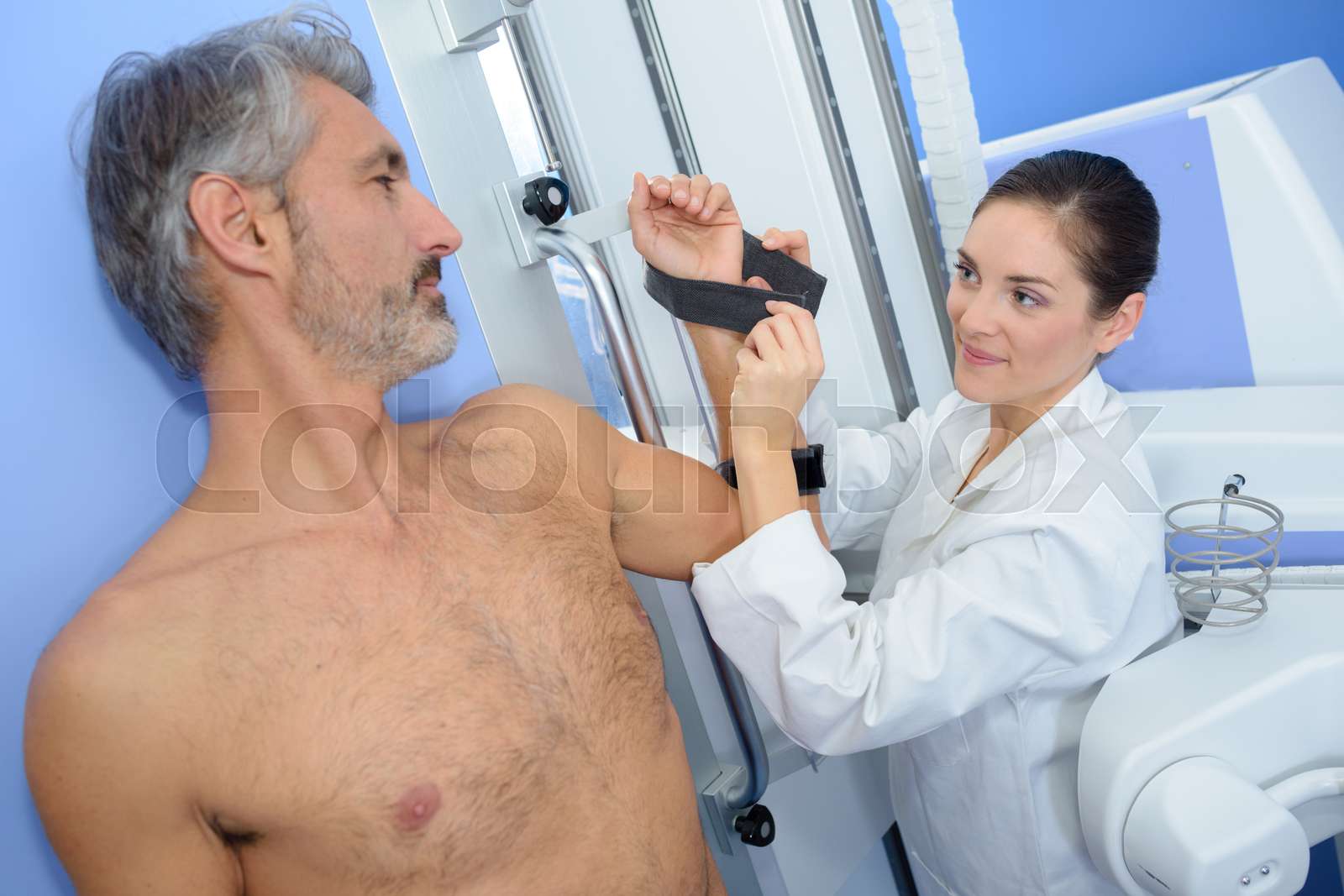 Nurse strapping man's arm for medical scan Stock image Colourbox