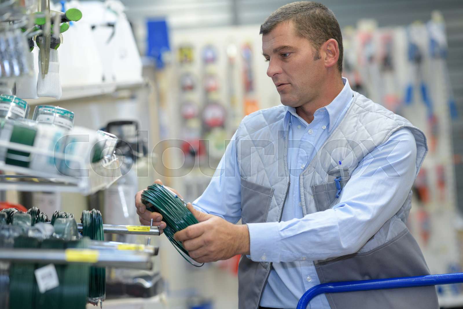 Man stocking shelf with plastic coated wire Stock image Colourbox