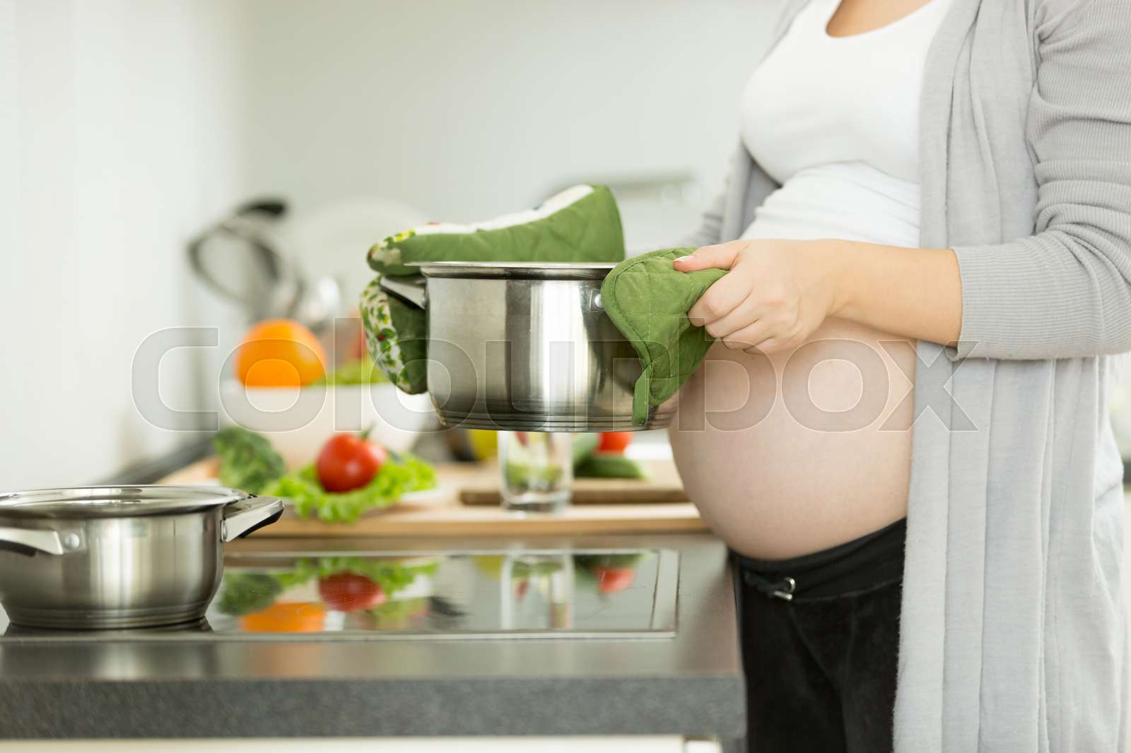 Pregnant woman posing on kitchen while cooking soup Stock image