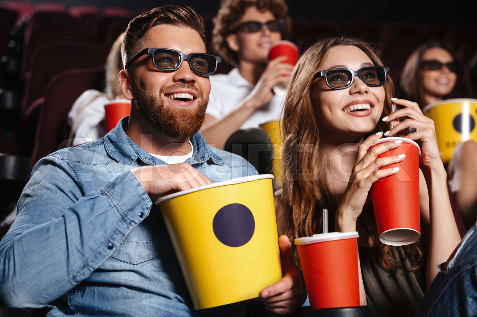 Happy friends sitting in cinema watch film | Stock image | Colourbox