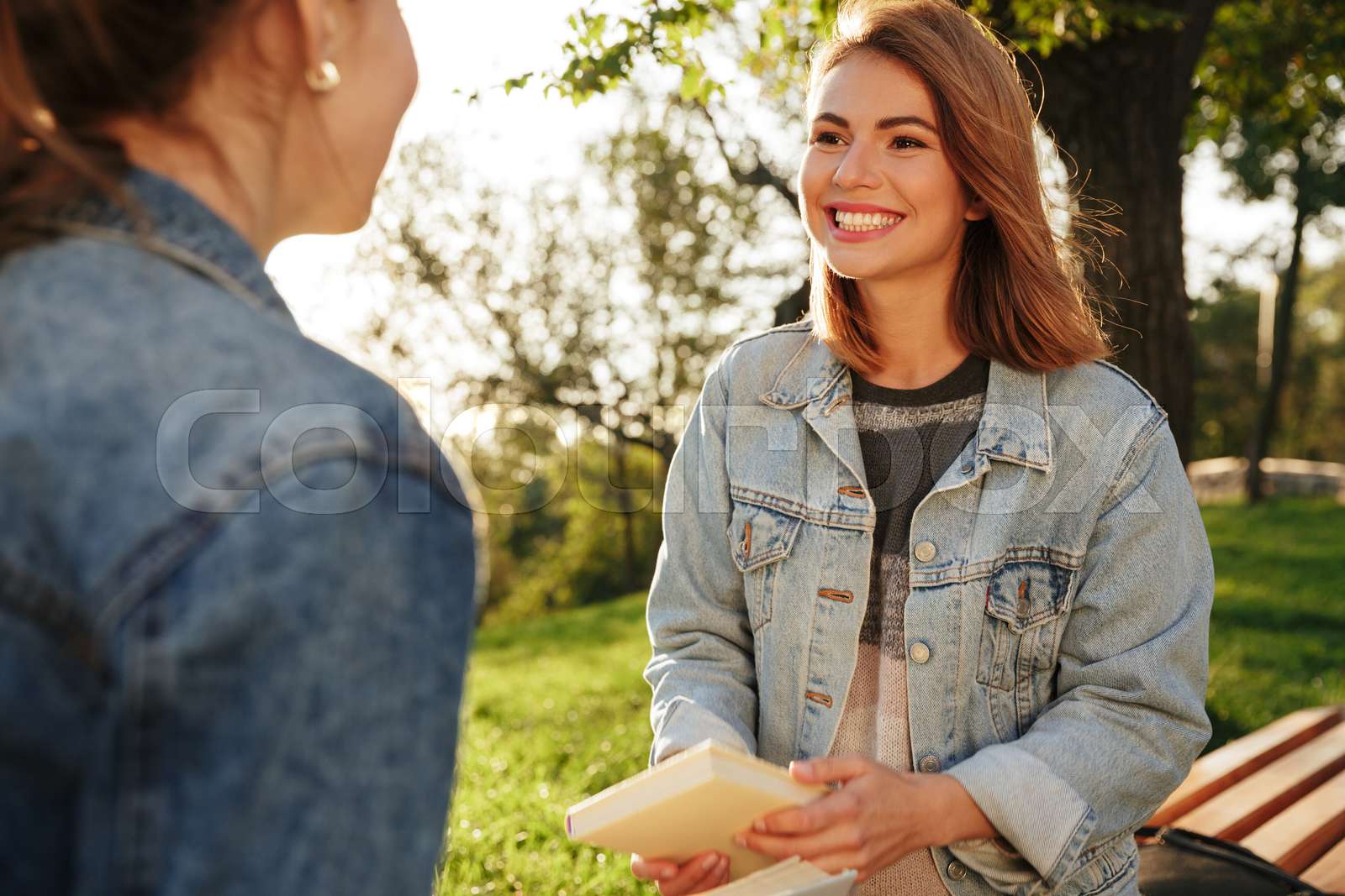 Closeup photo of two happy attractive woman discussing a book in park