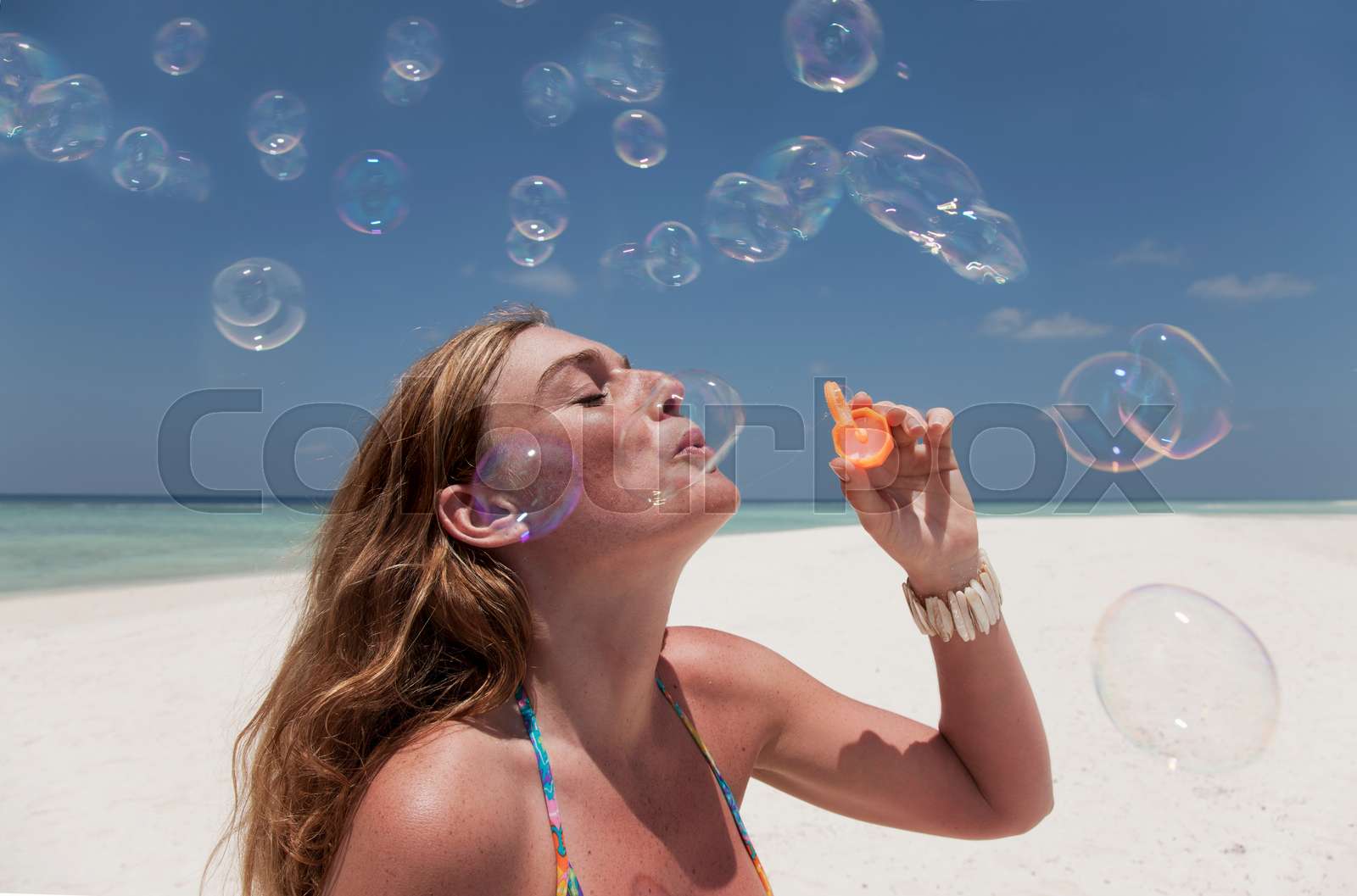 Woman blowing bubbles on beach Stock image Colourbox