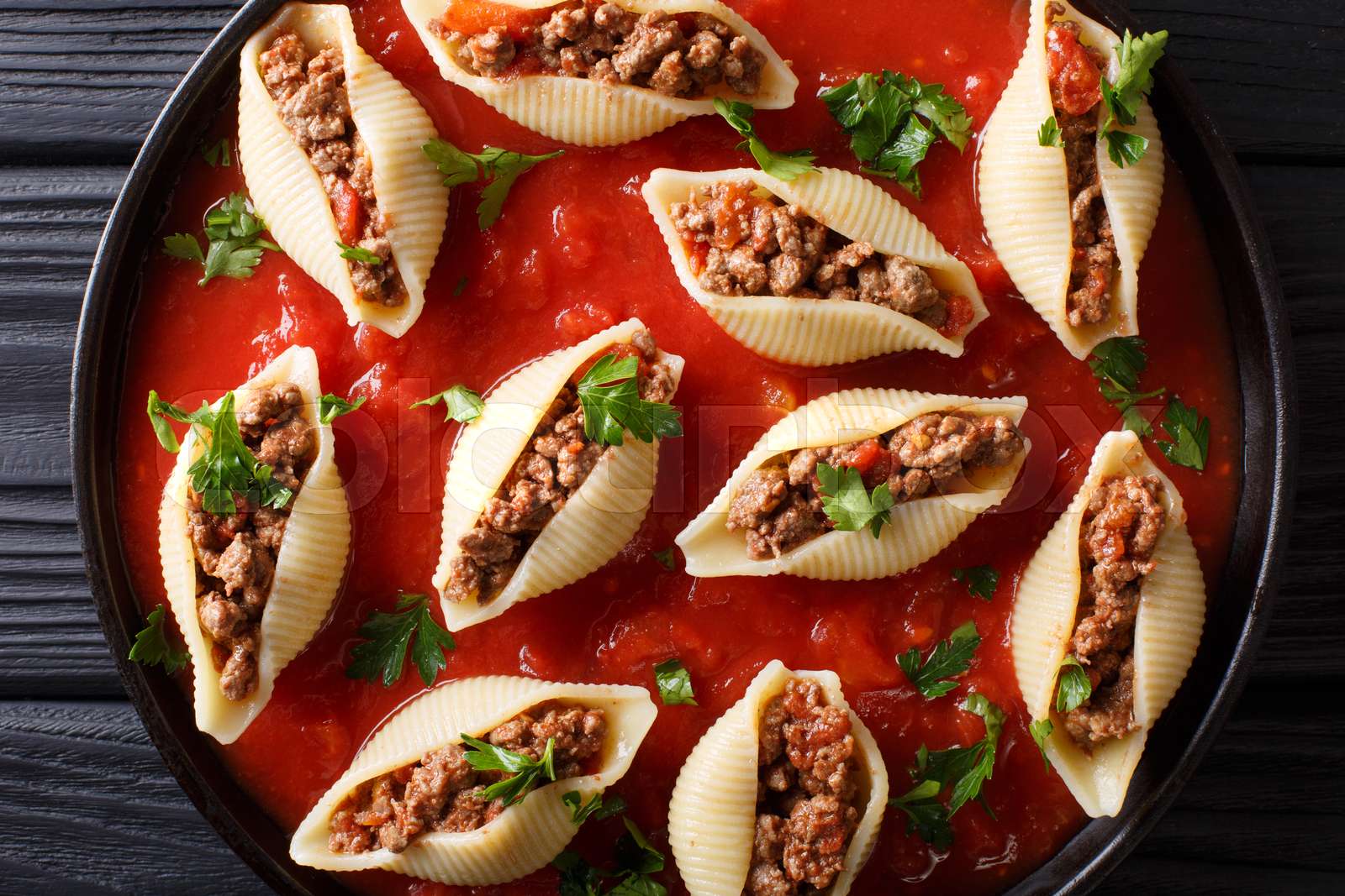 Pasta shell conchiglioni with minced meat filling in marinara sauce