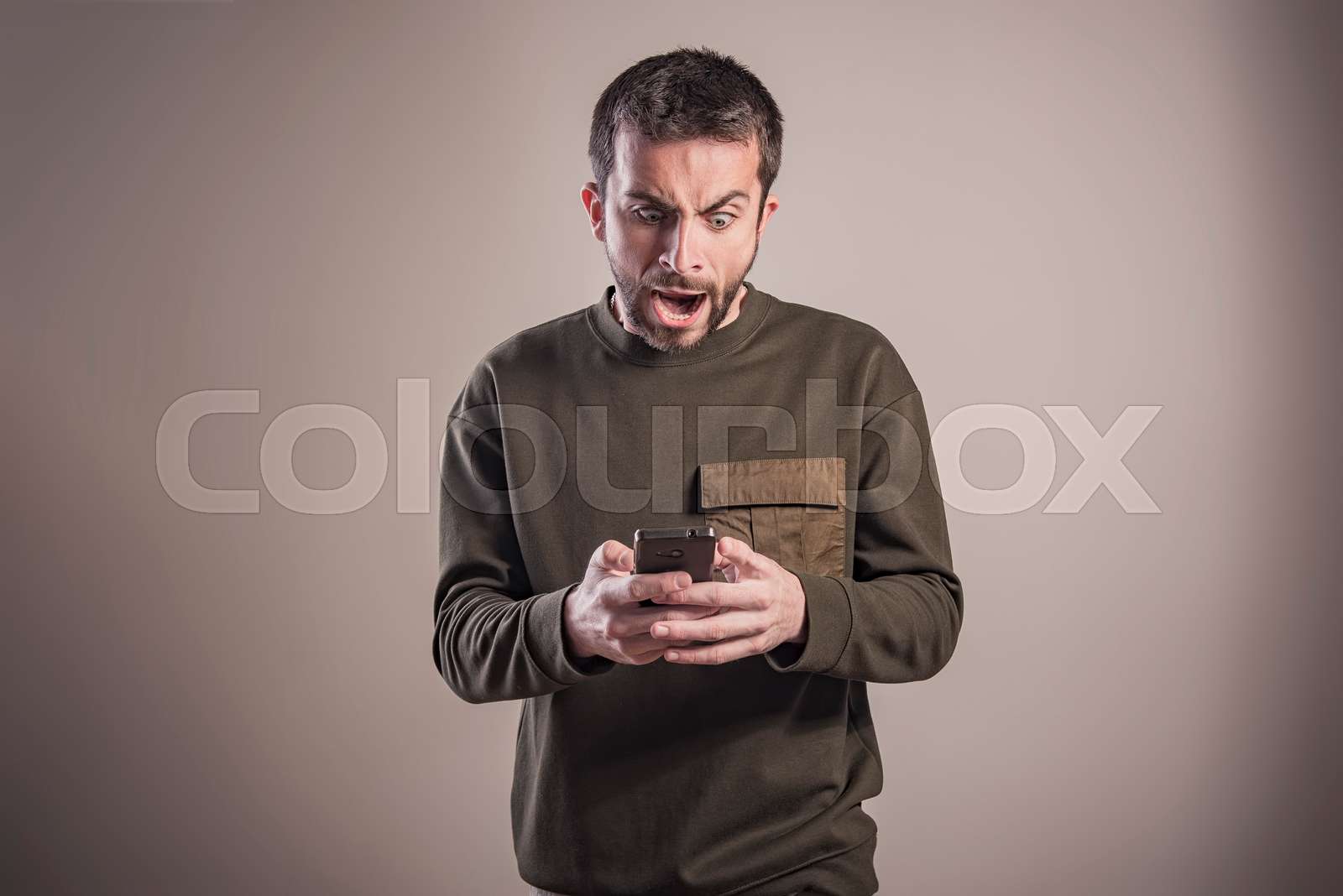 Man angry at his phone, outraged and enraged Stock image Colourbox