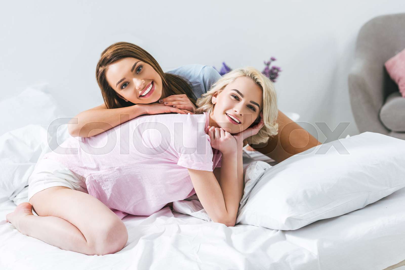 two cheerful girls having fun on bed in the morning Stock image
