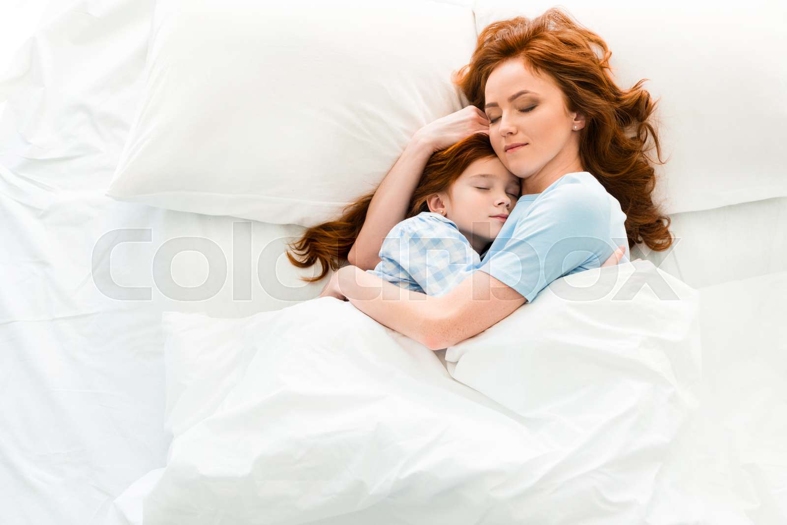 Beautiful mother and daughter hugging and sleeping together in bed