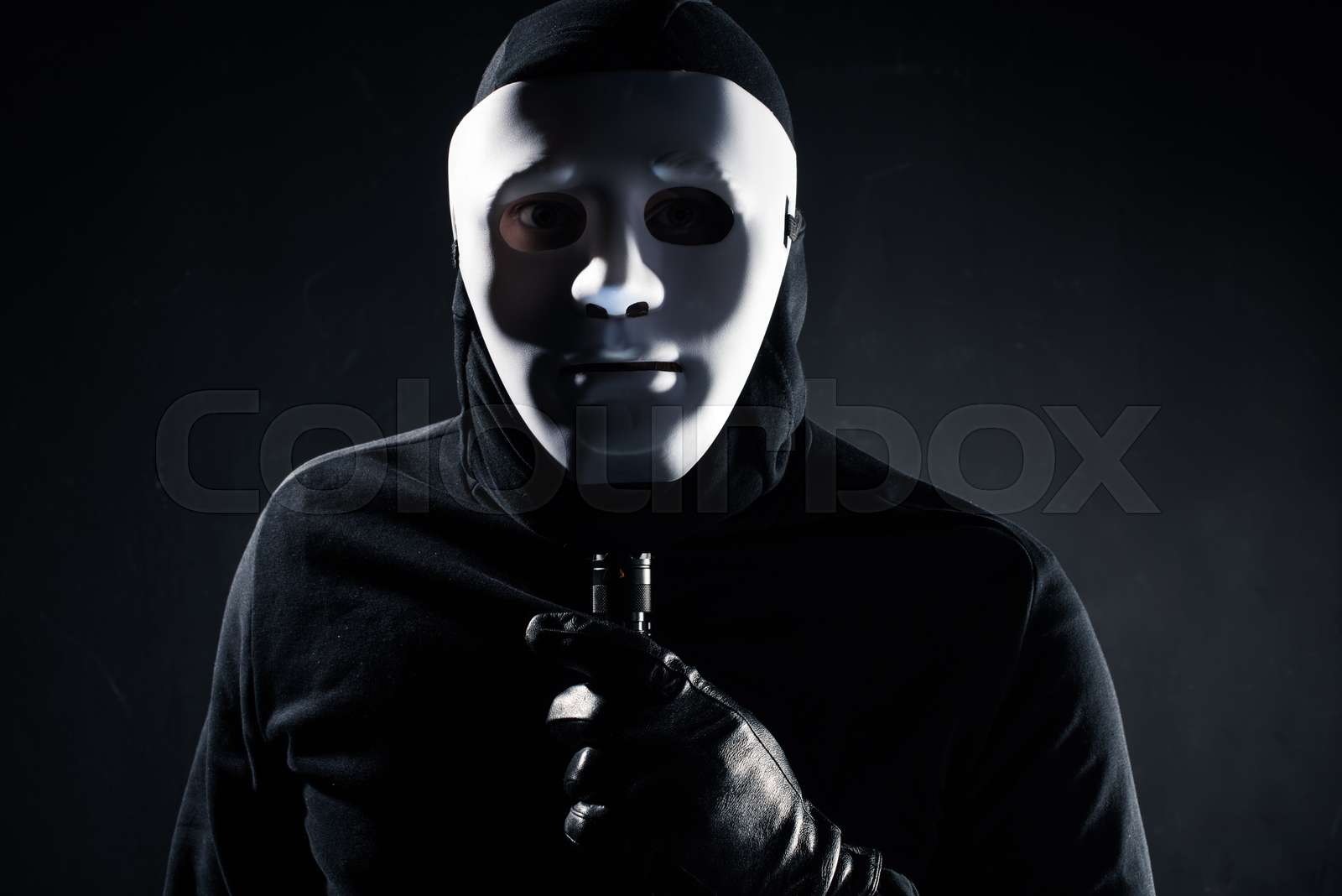 Robber in white mask holding flashlight | Stock image | Colourbox