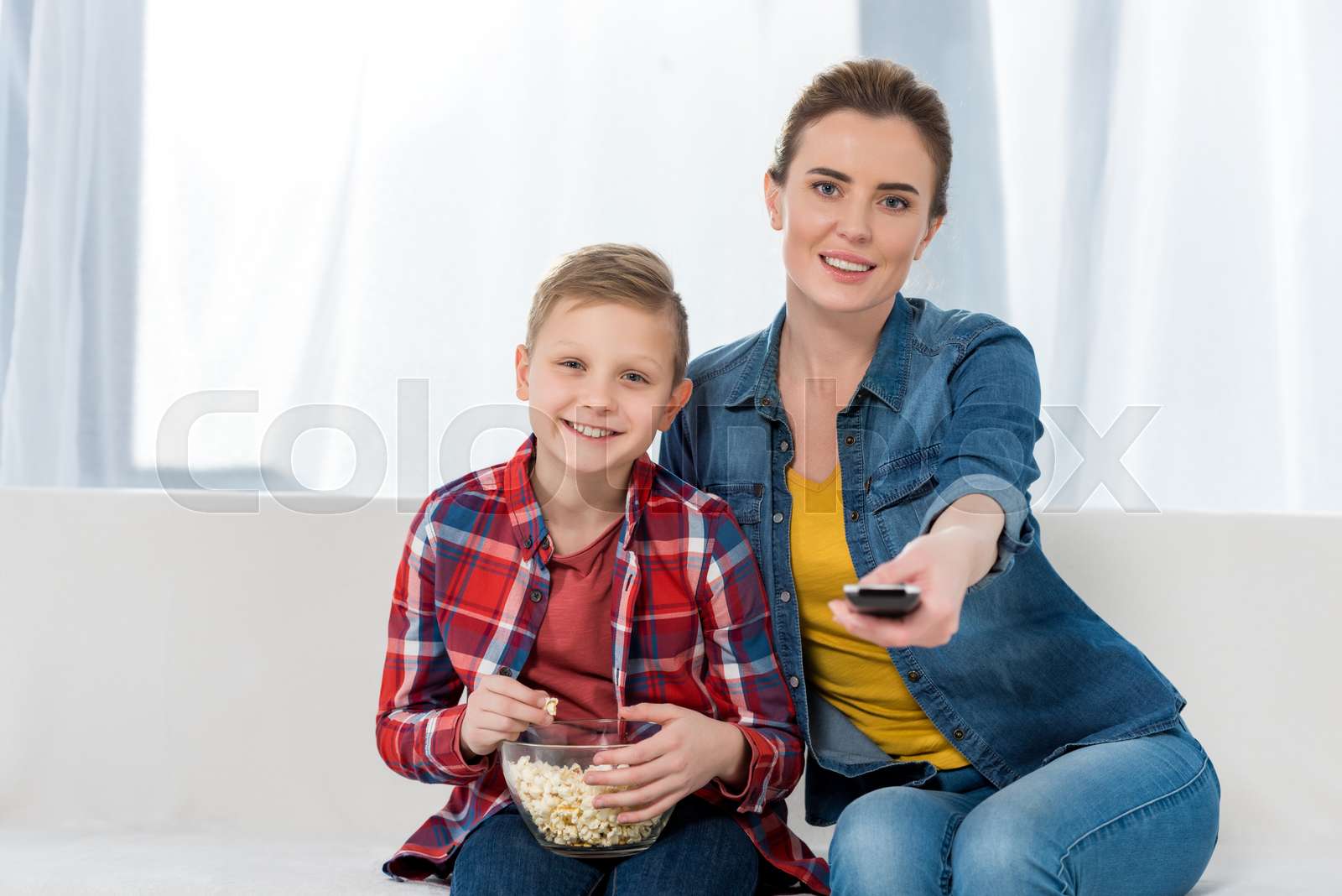 happy mother and son watching tv together with popcorn | Stock image