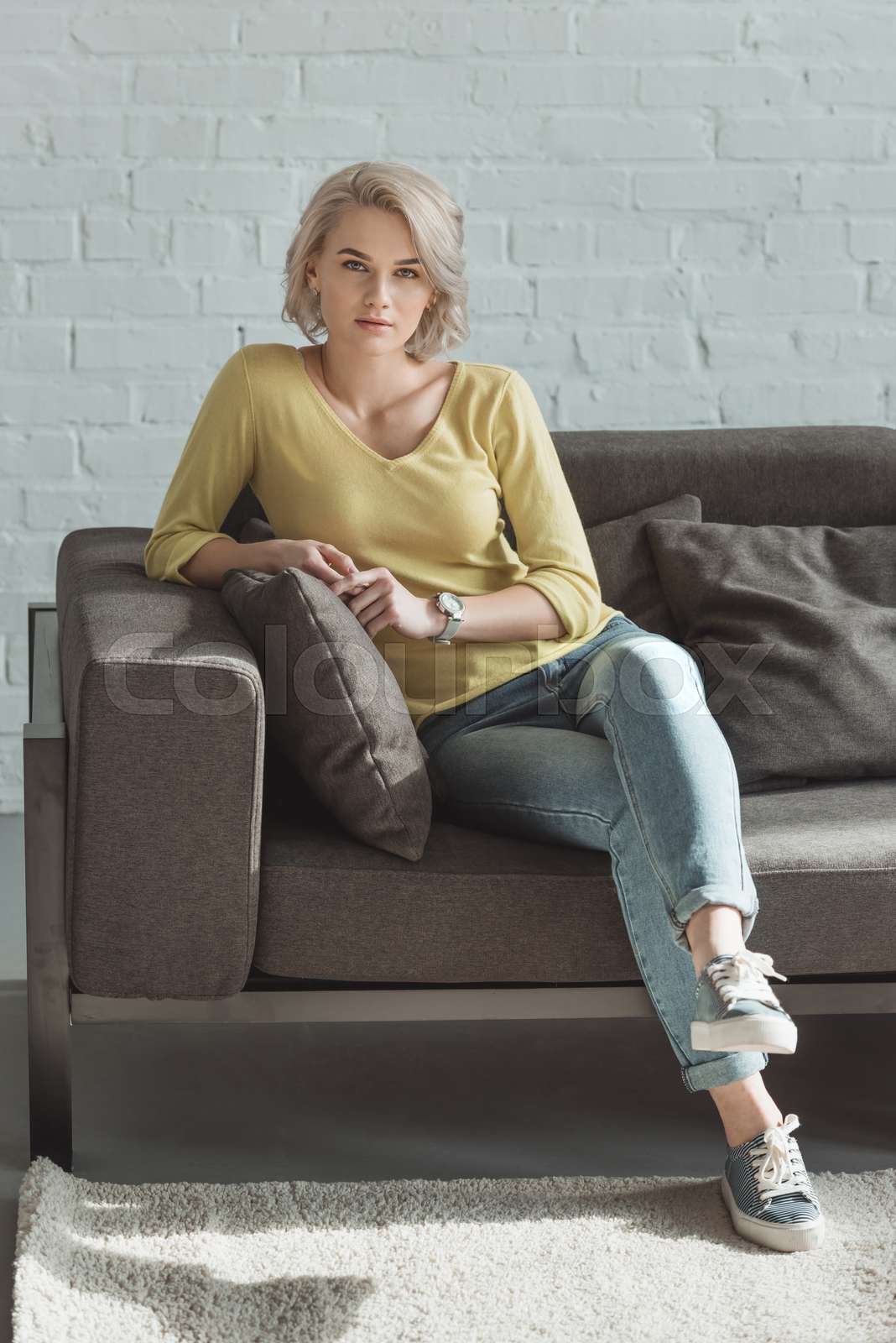 beautiful girl sitting on sofa and looking at camera | Stock image ...