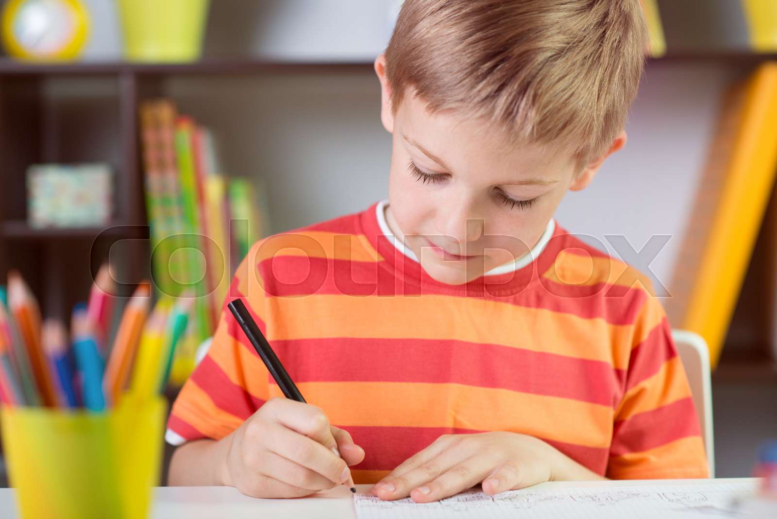 School boy at classroom desk making schoolwork stock image colourbox