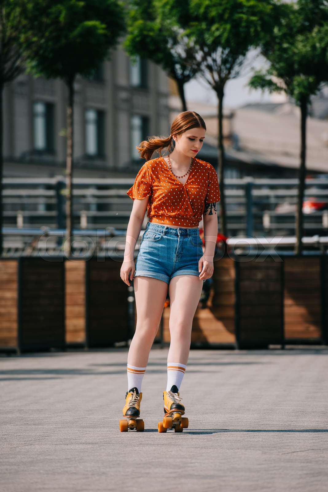 beautiful stylish girl in denim shorts roller skating on street Stock