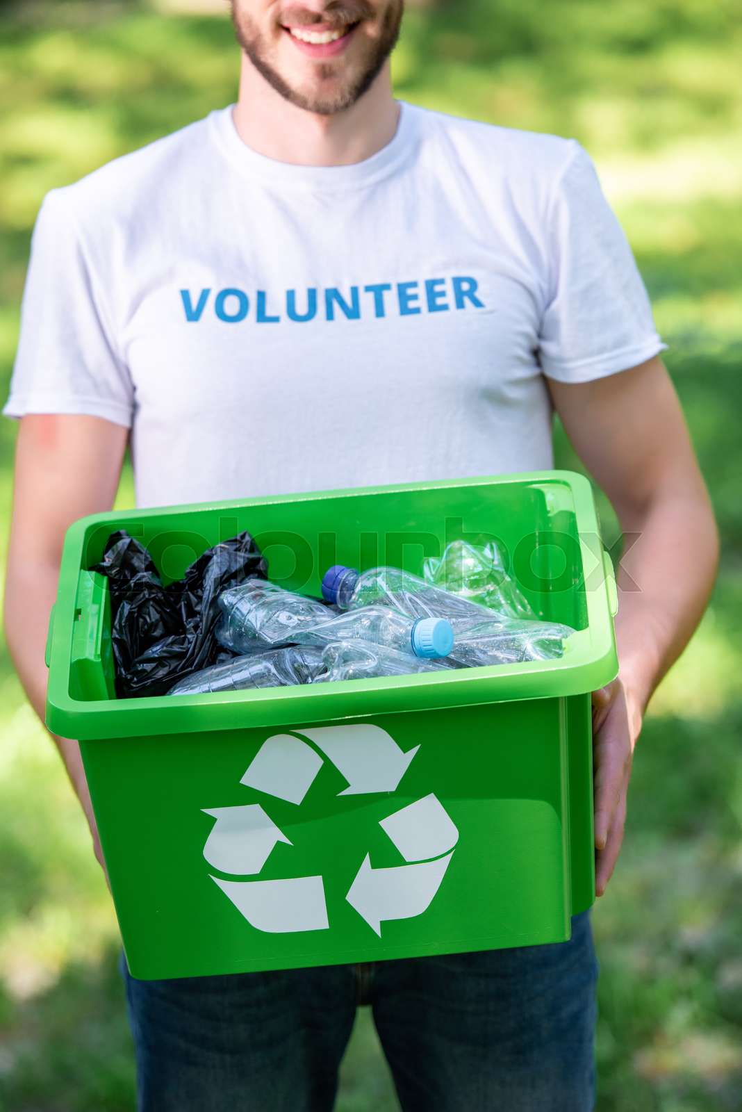 partial view of smiling volunteer holding recycling box with plastic