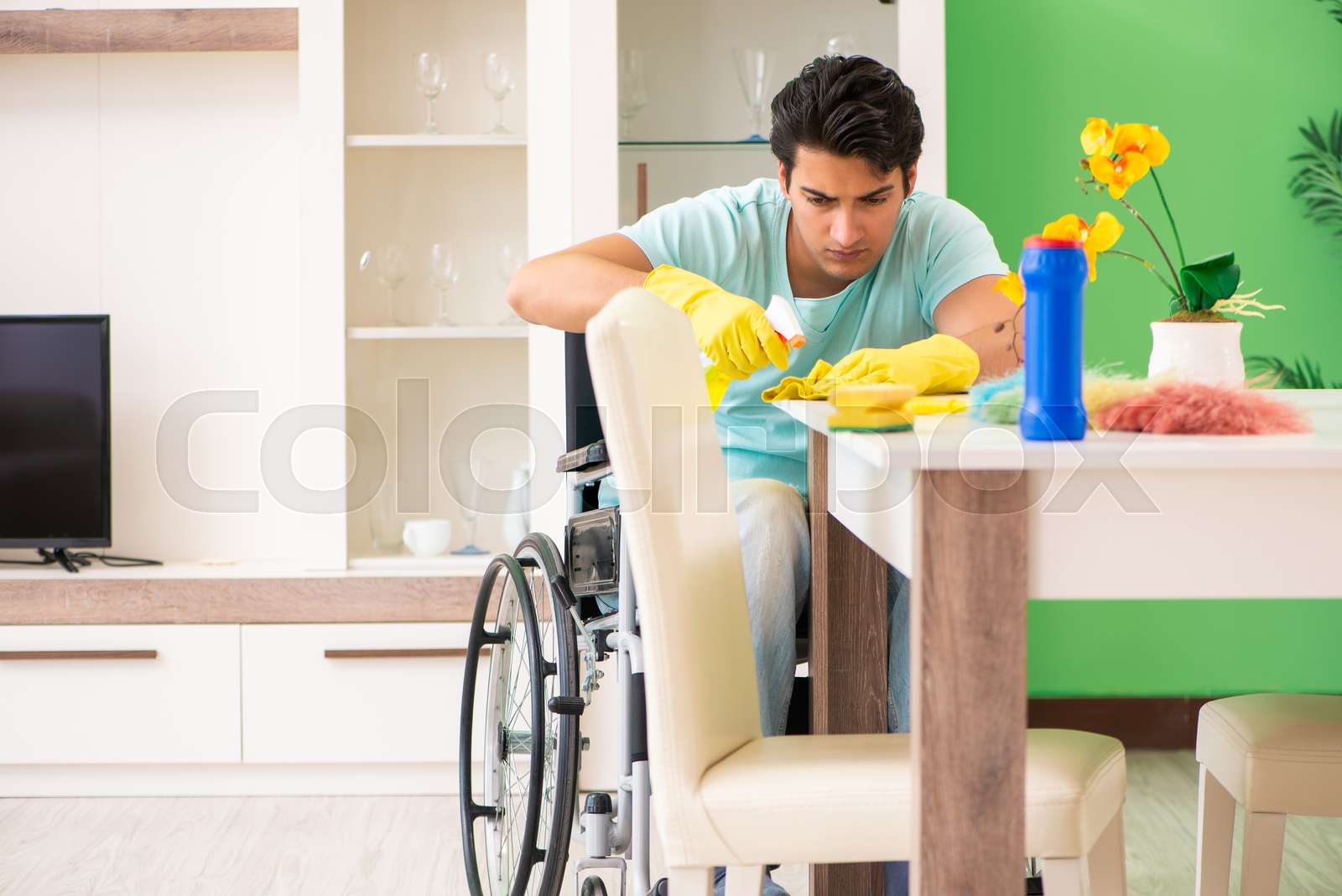 Disabled man on wheelchair cleaning house Stock image Colourbox