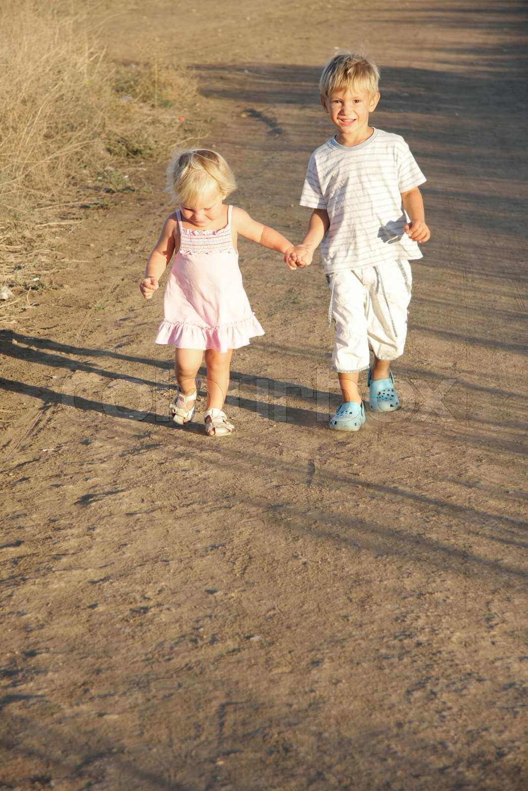 young brother and sister walking by country road | Stock image | Colourbox