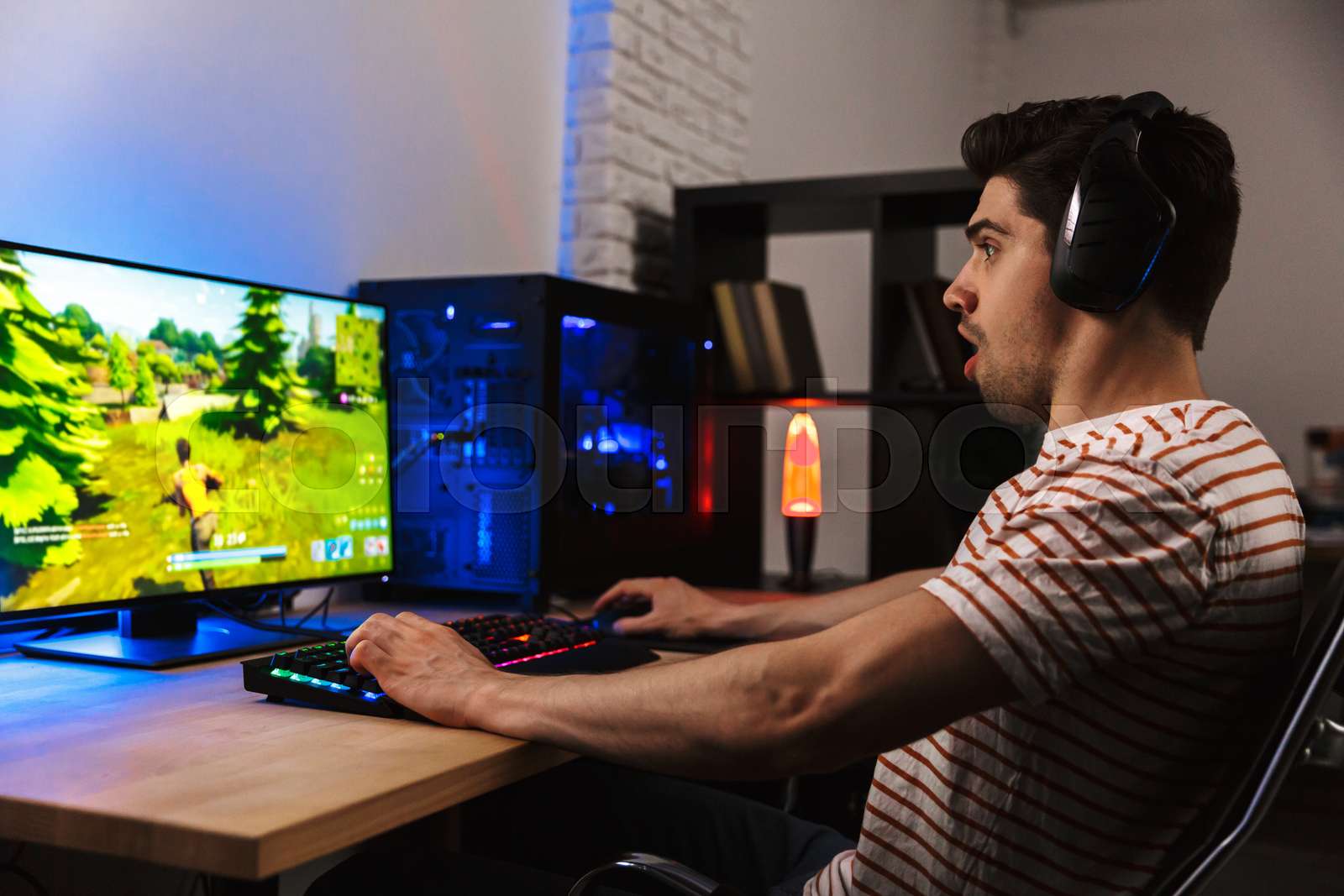 Image of excited guy in headphones playing video games on computer ...